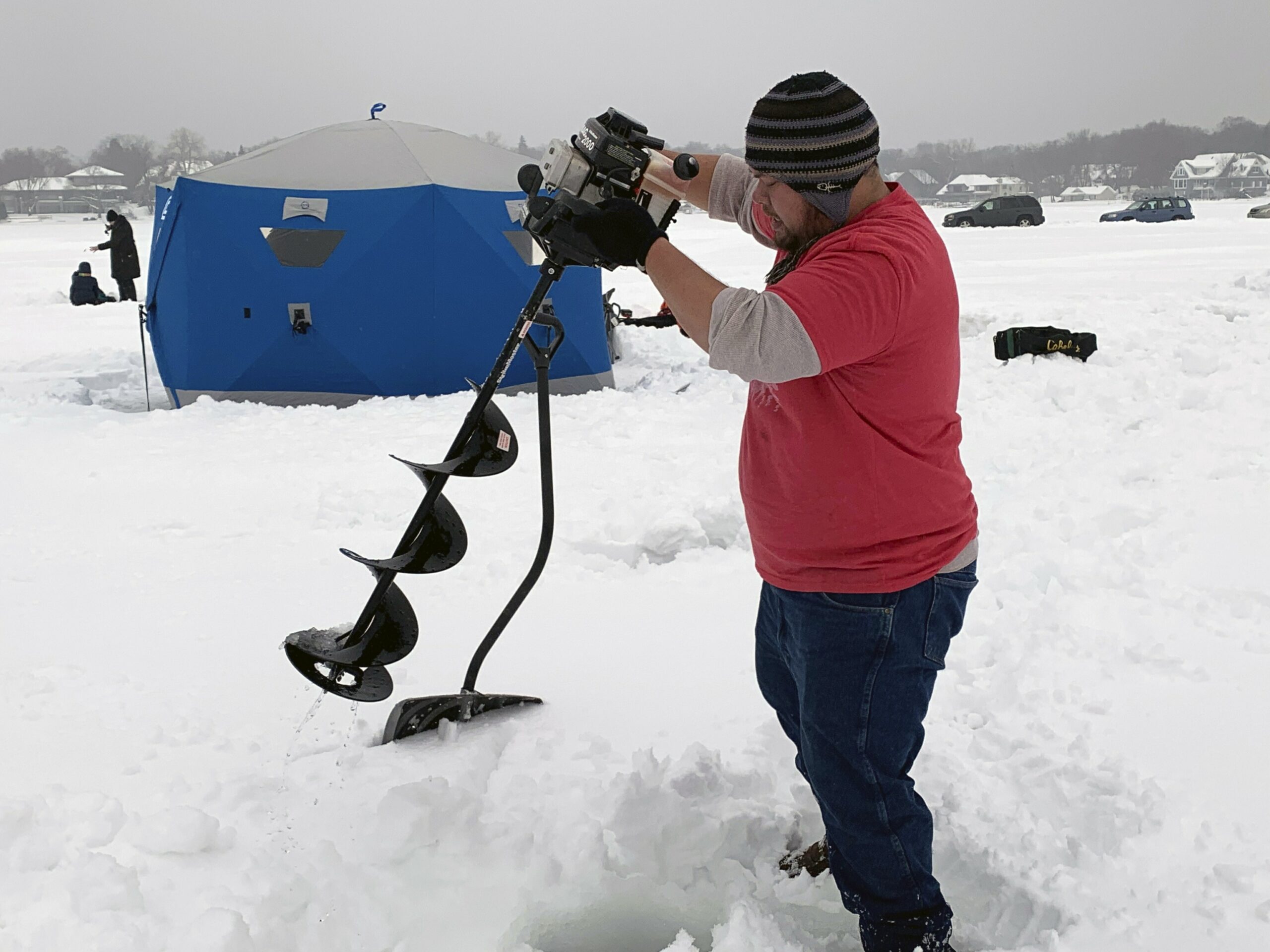 Jason Kong uses an auger to drill holes in Lake Minnetonka to ice fish