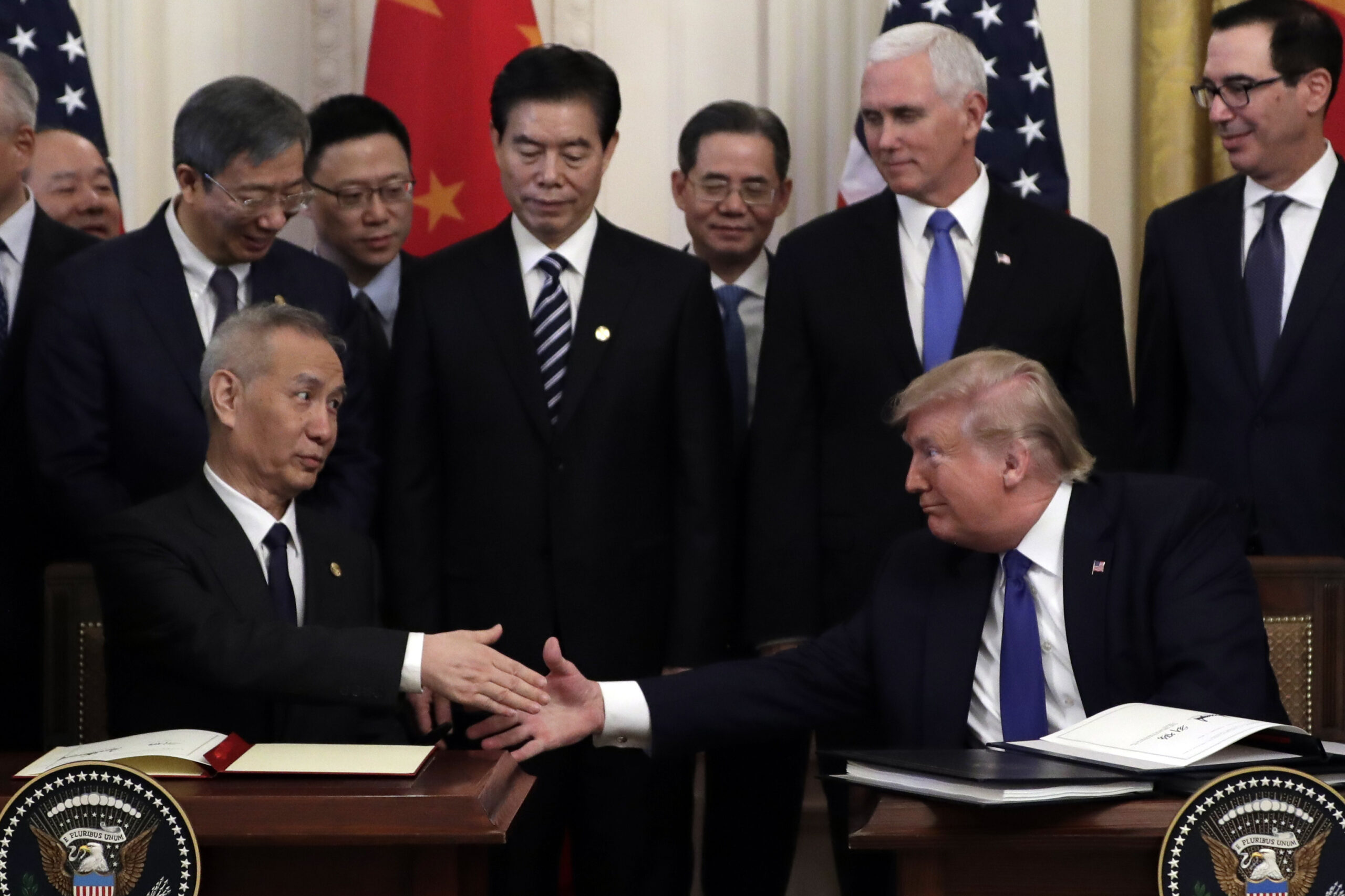 On left, Vice Premier Liu He reaches out to shake hands with President Donald Trump, on right. Behind them stand several men, including Vice President Mike Pence.
