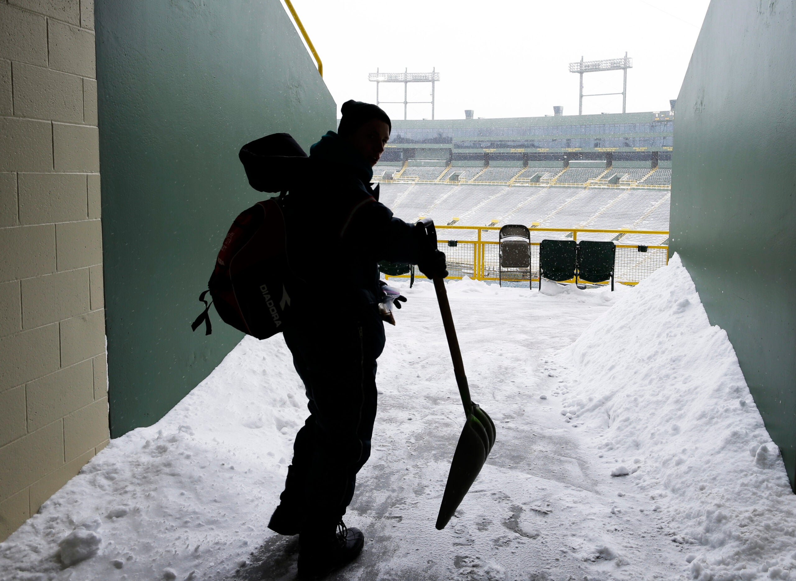 A person shoveling snow at Lambeau Field