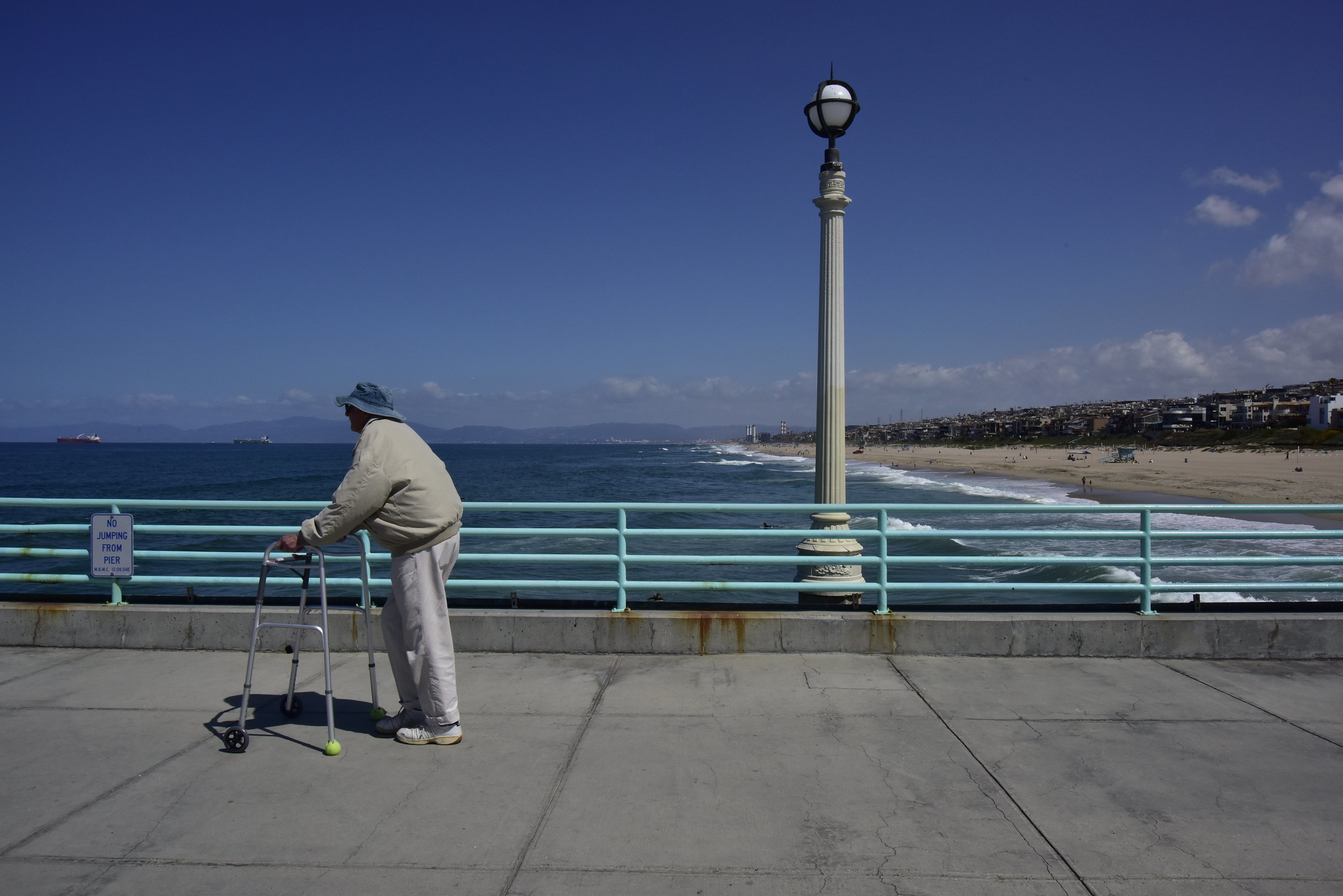 An elderly man walks on a pier
