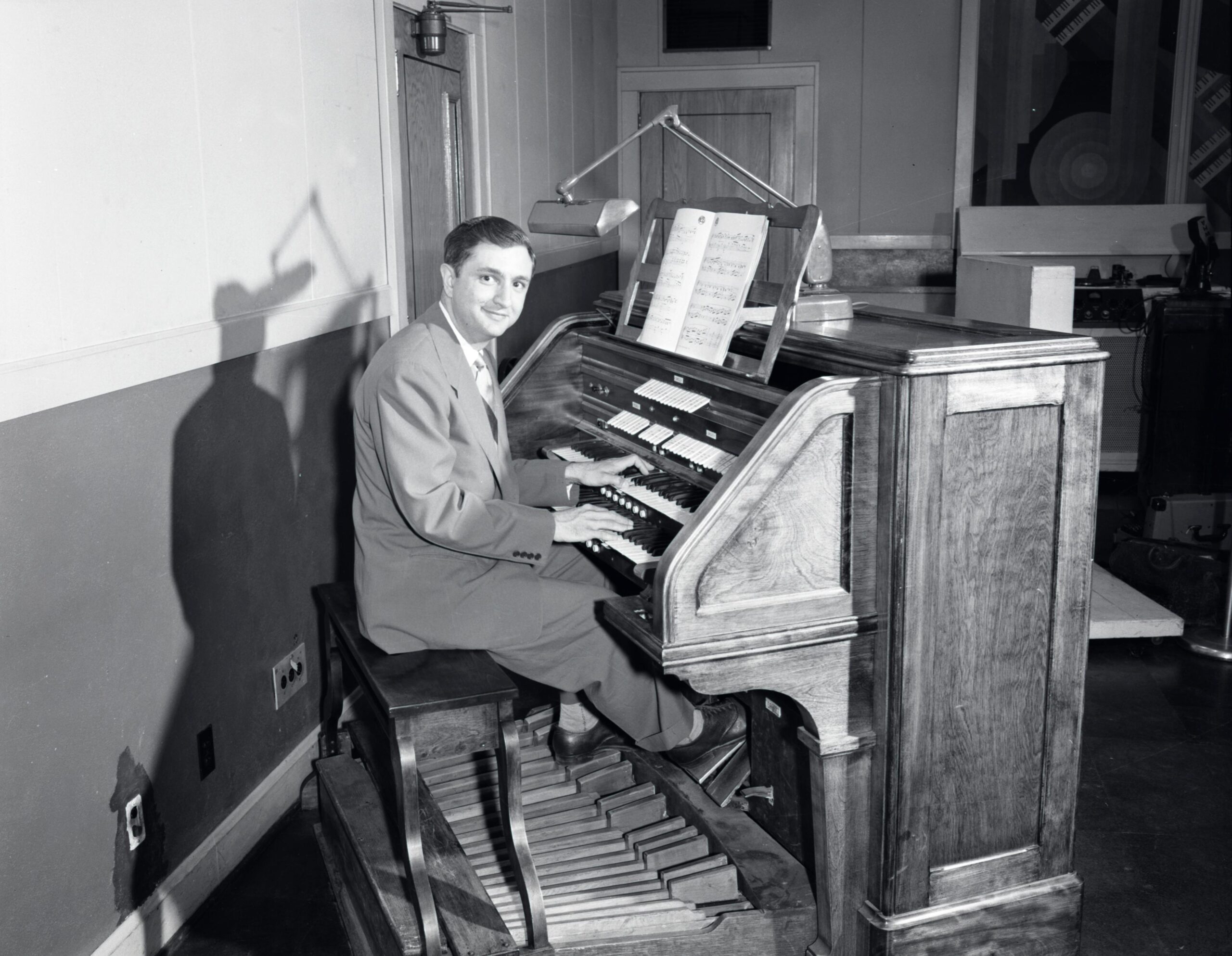 Composer Don Voegeli poses for a picture at a small organ in the WHA studio.