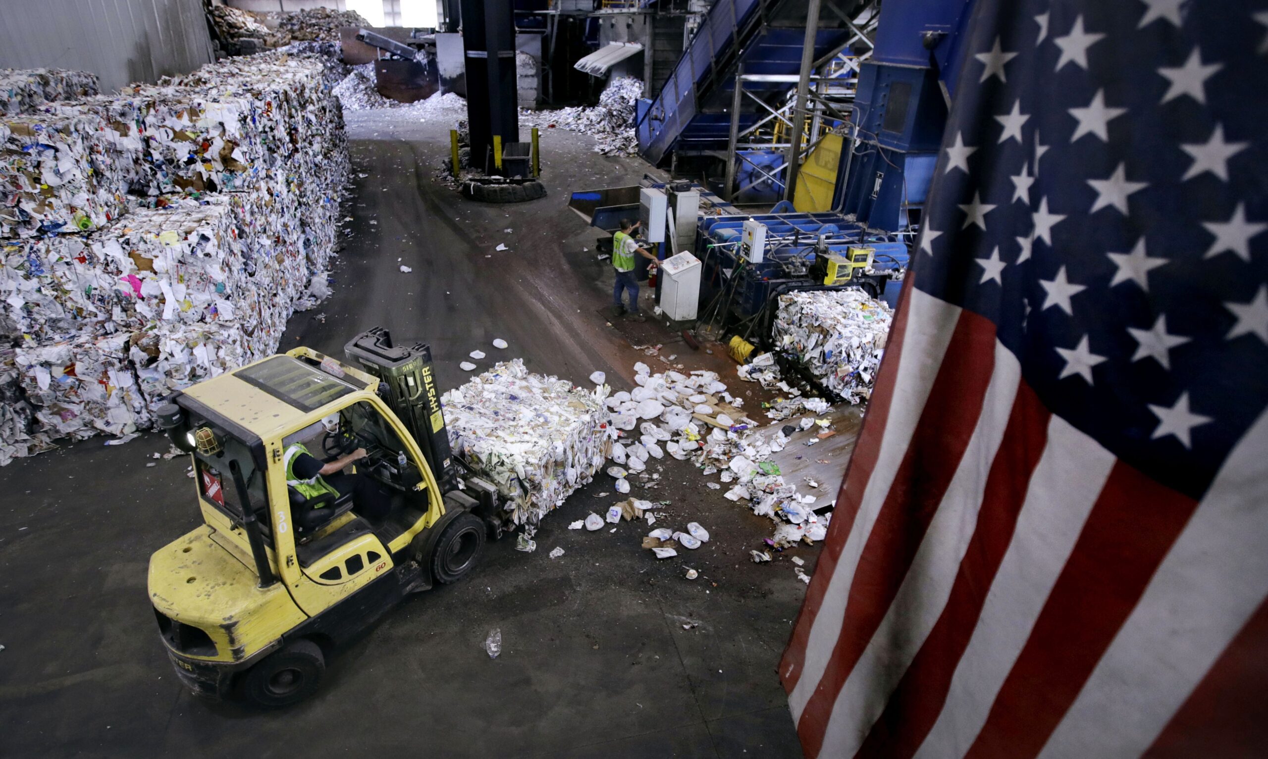 A forklift carries a bundle of recycled materials