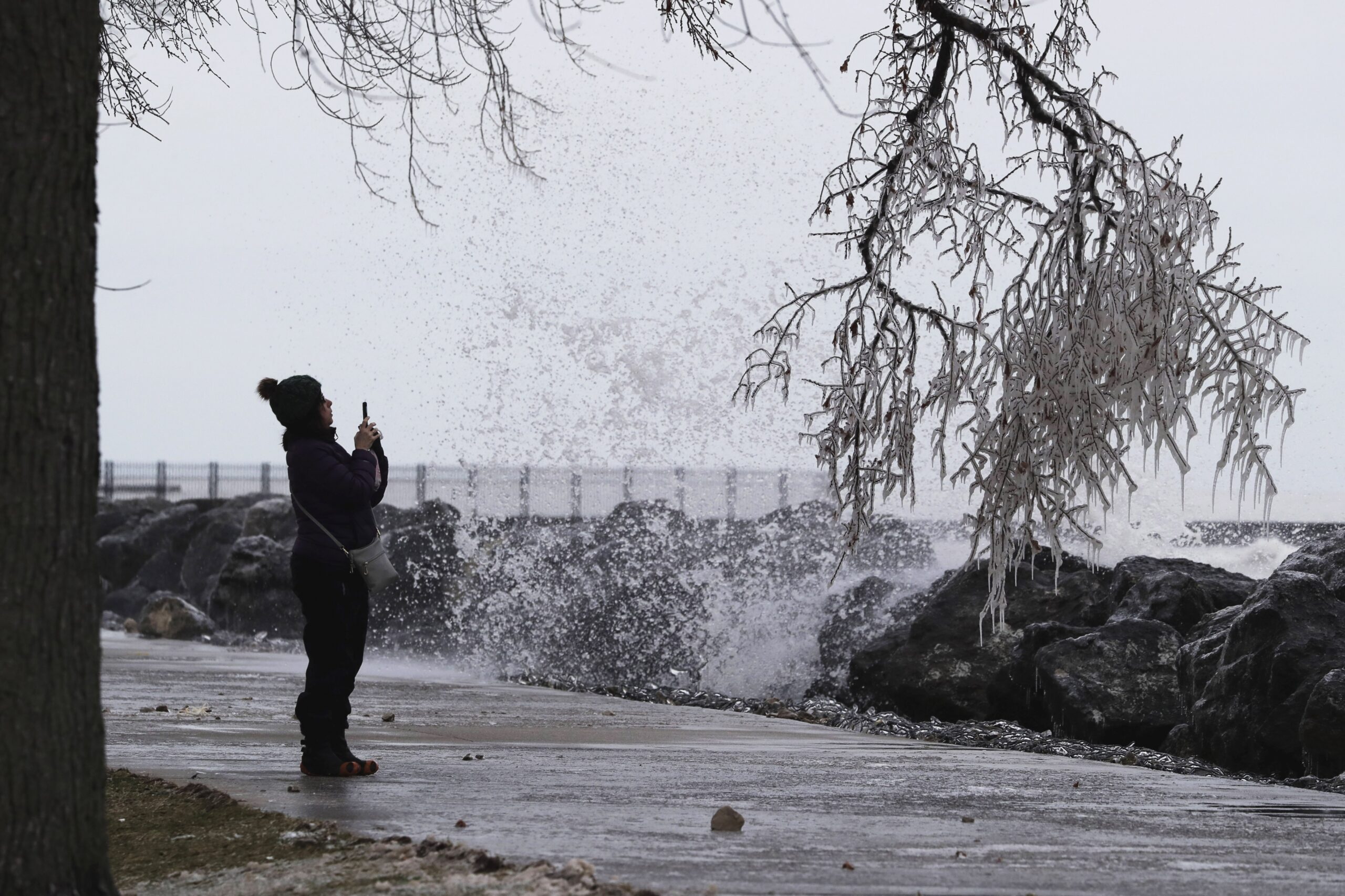 A woman takes photos of the shore of Lake Michigan.