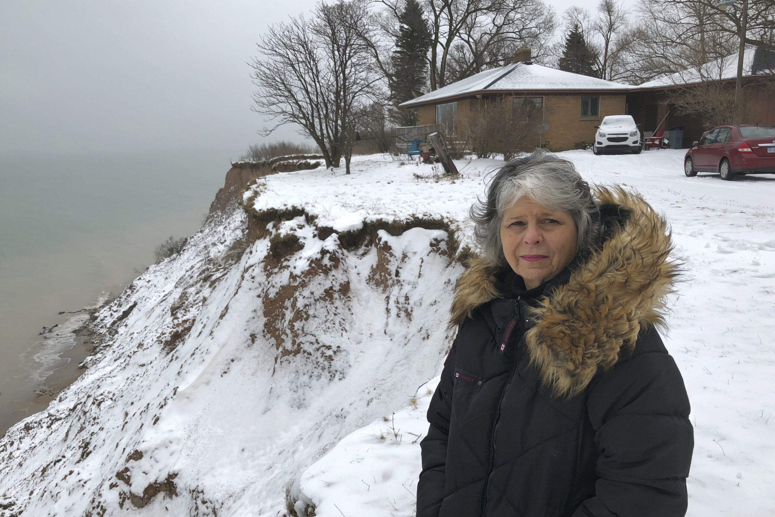 Rita Alton stands next to her house on Lake Michigan