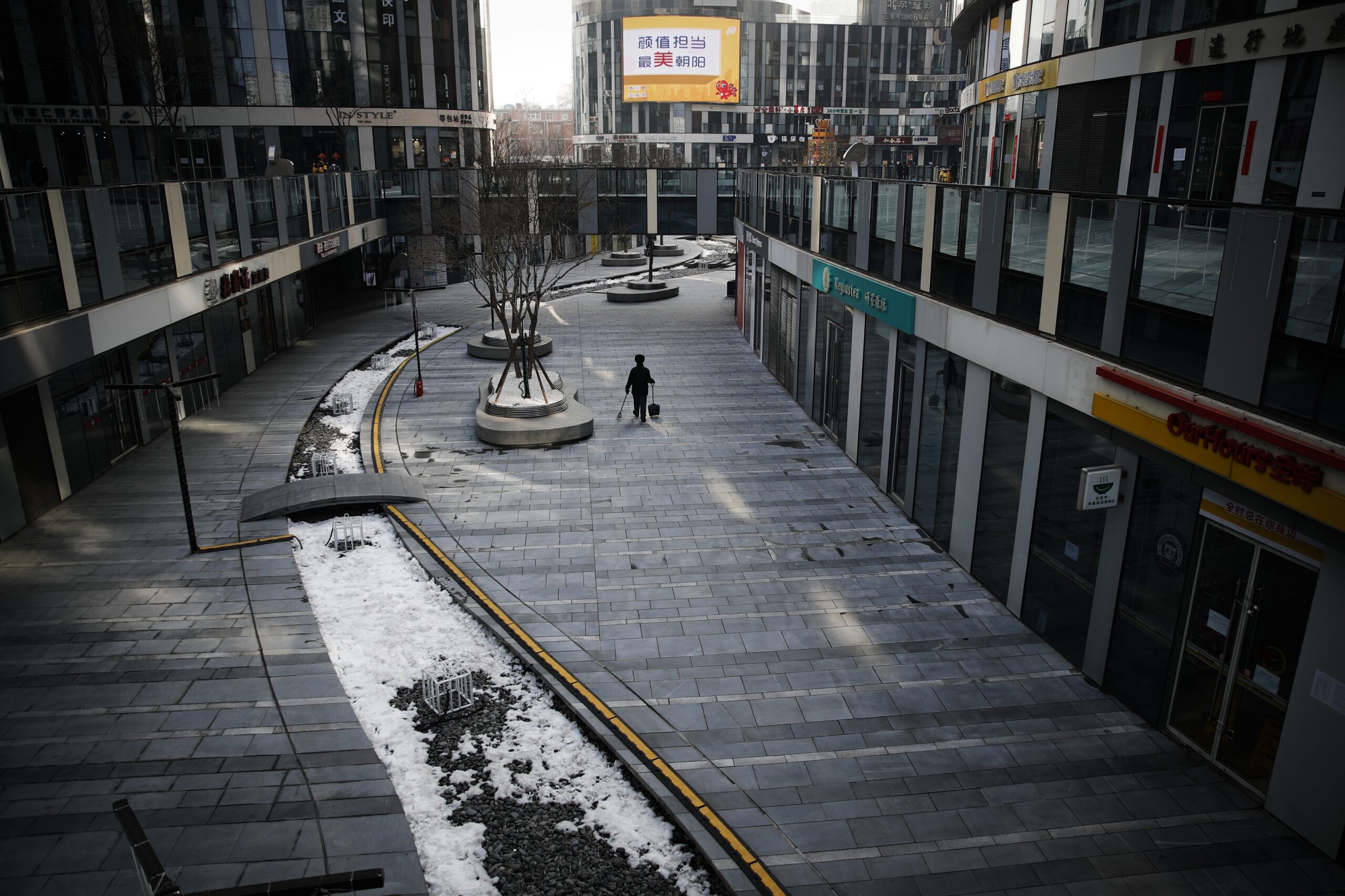 A cleaner walks through a deserted compound of a commercial office building