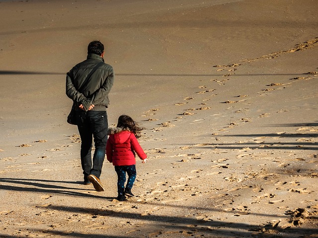 father and daughter walking on a beach