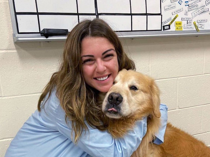 Scout snuggles with a veterinary student