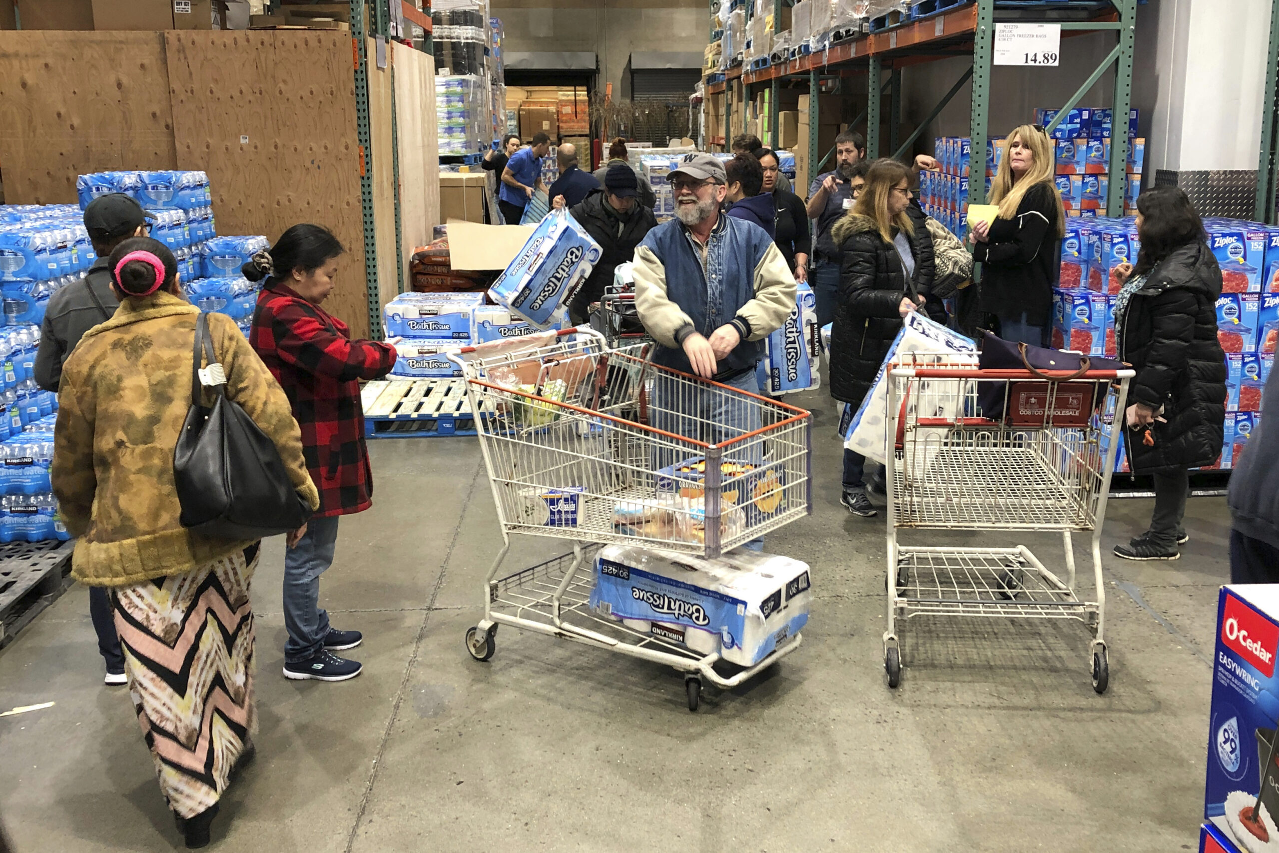 Shoppers wait their turns to pick up toilet paper that had just arrived at a Costco store