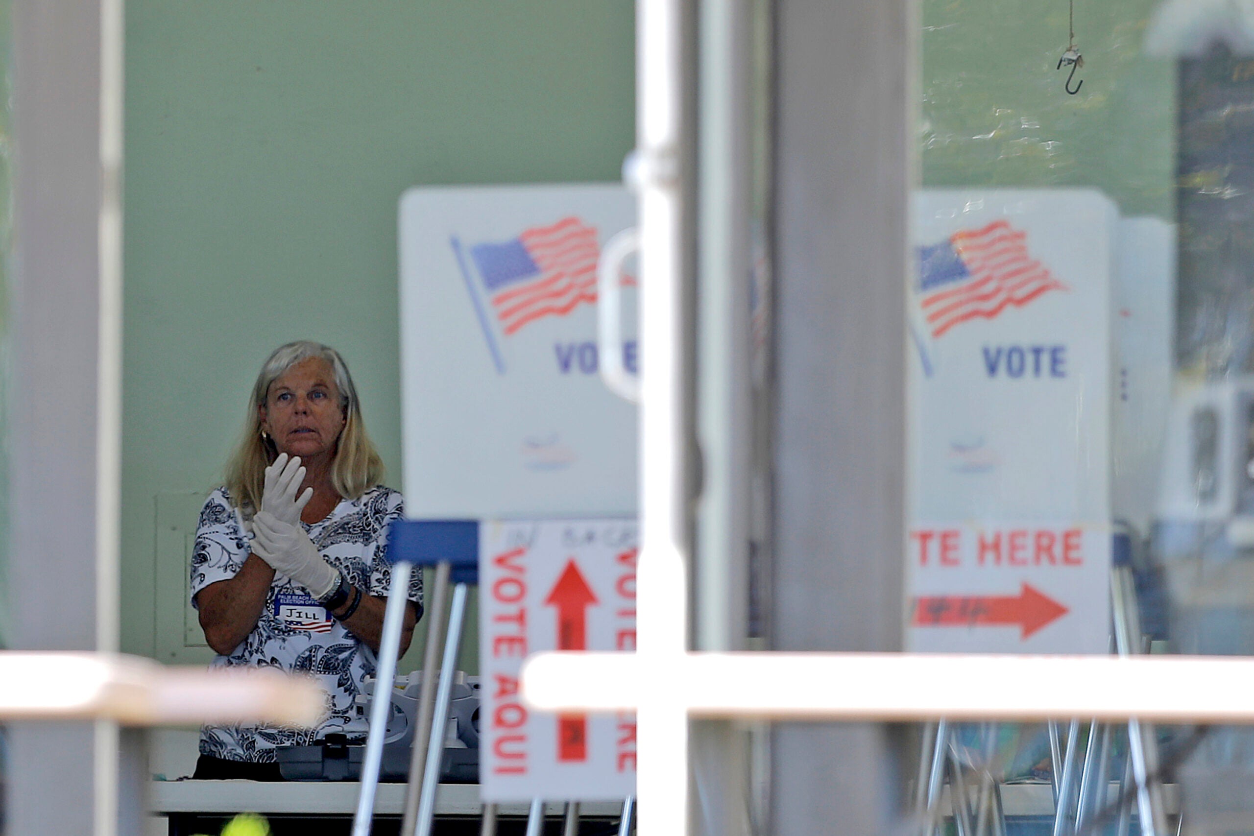 A polling place worker adjusts gloves as she tends to a reception table