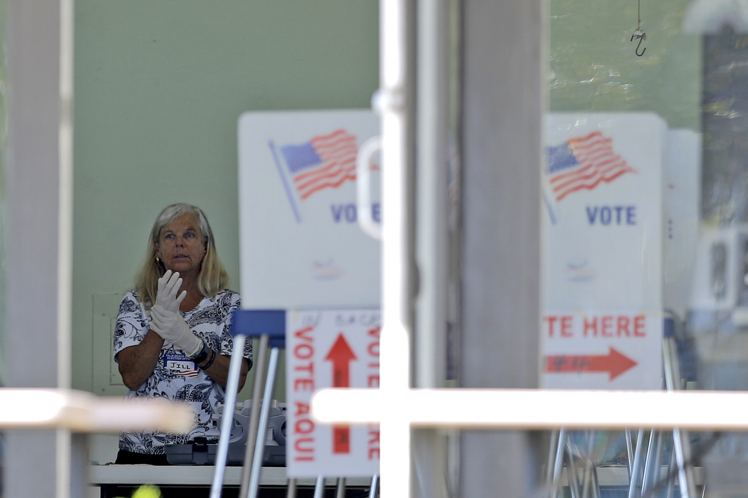 A polling place worker adjusts gloves as she tends to a reception table