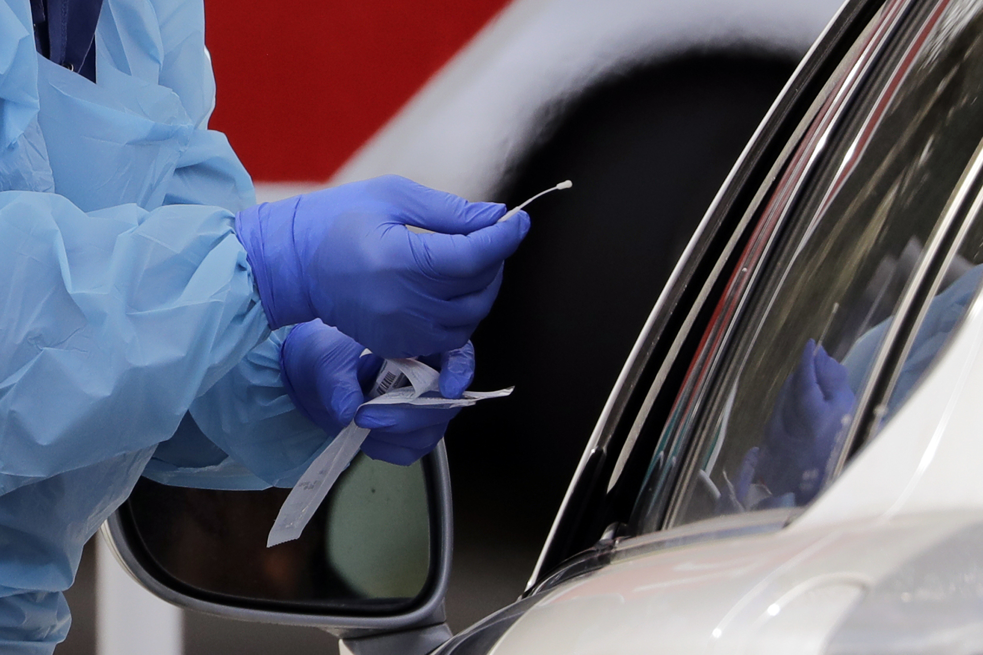 Nurse completes taking a nasopharyngeal swab from a patient at a drive-through COVID-19 testing station f