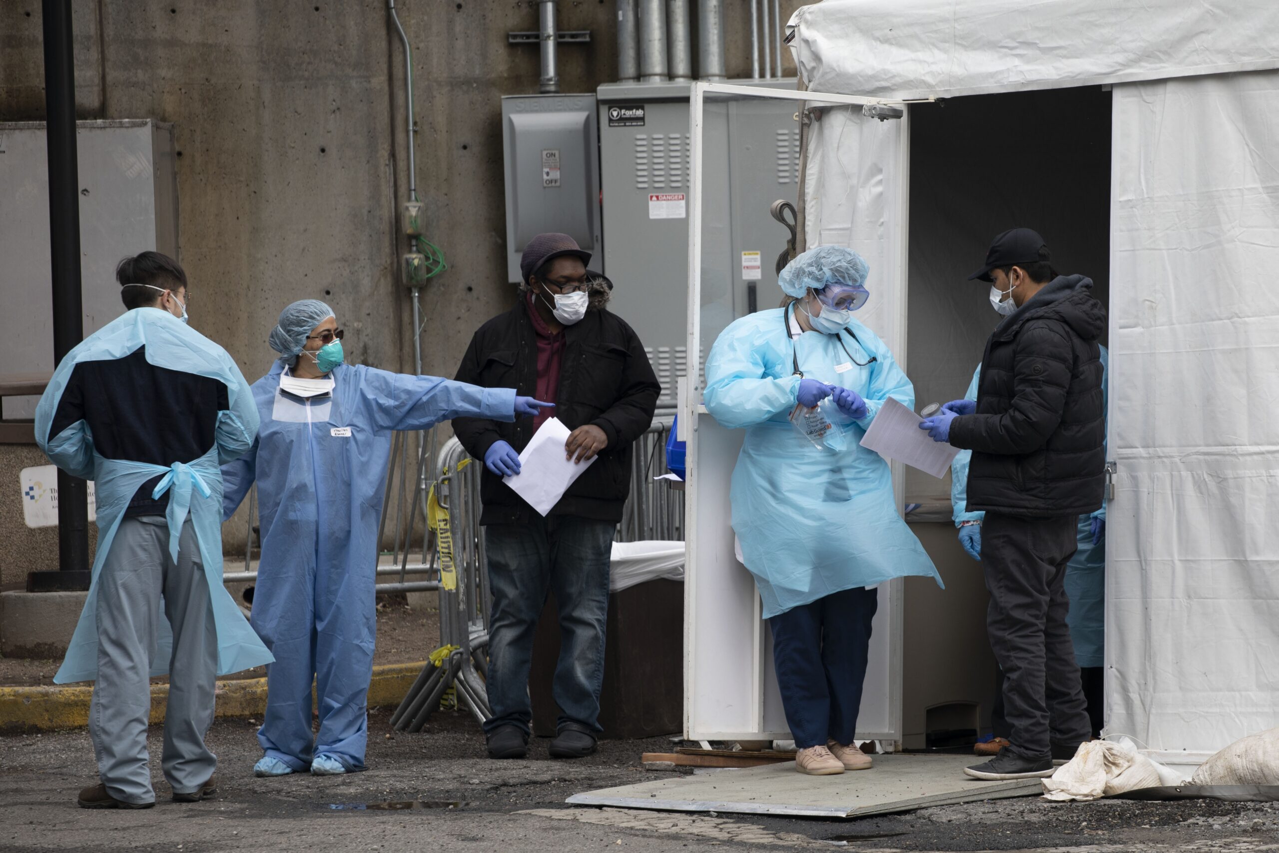 Hospital personnel assist people at a coronavirus screening tent outside the Brooklyn Hospital Center