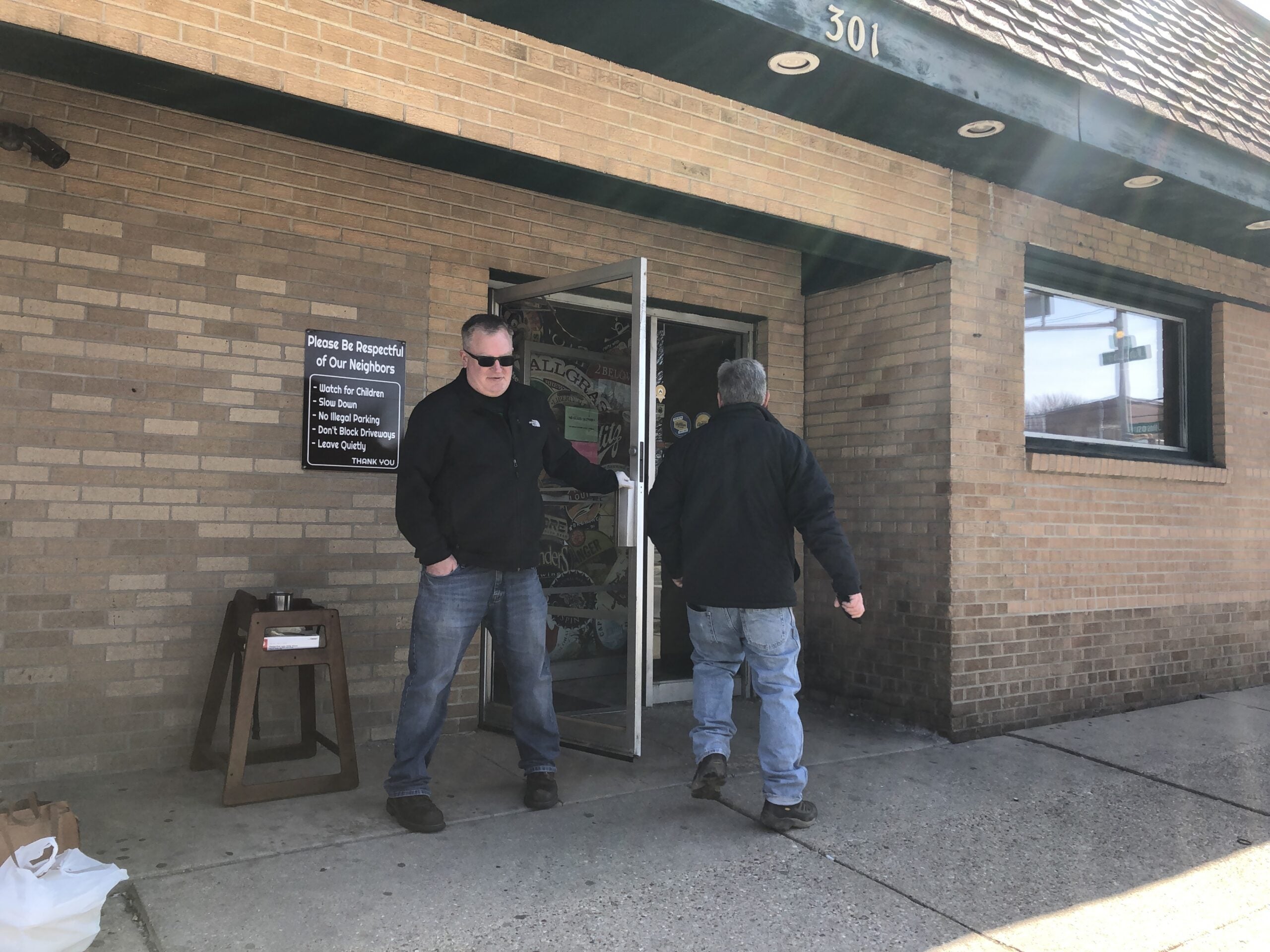 A man holds open a restaurant door.