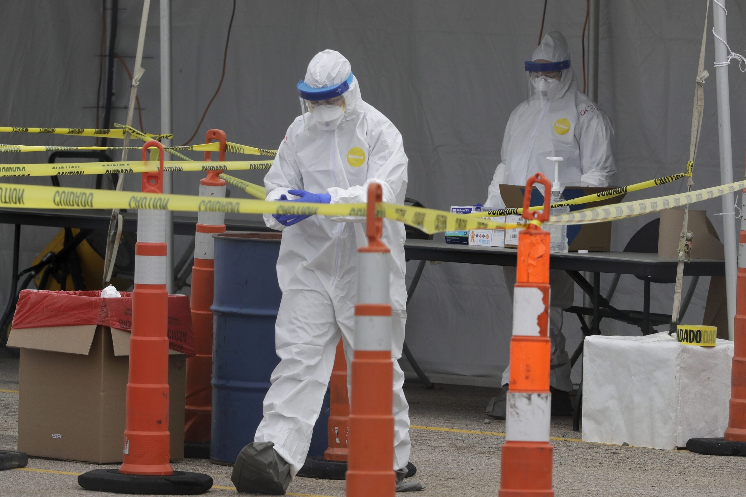 A medical worker in protective garments adjusts their gloves