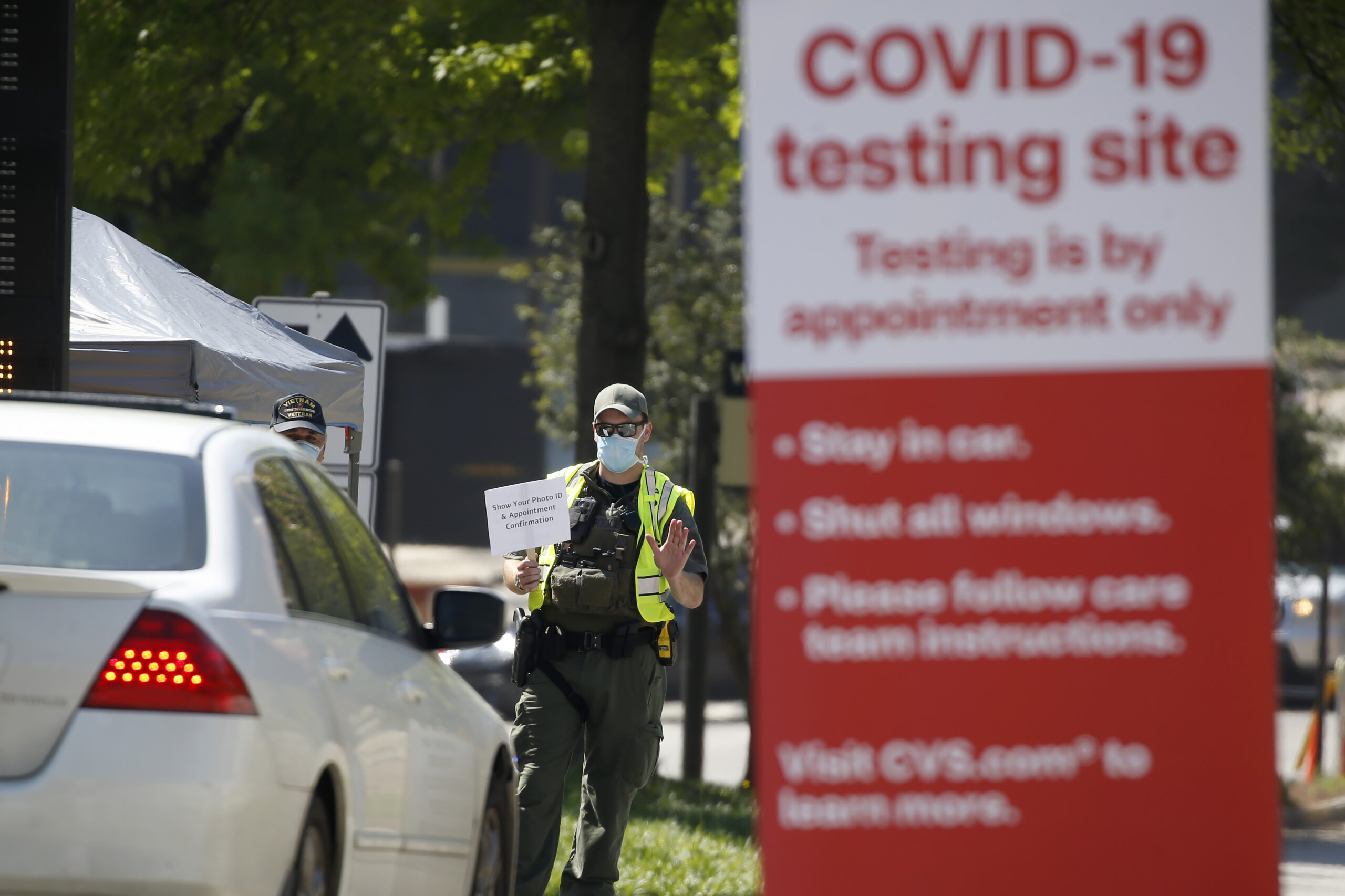 A police officer directs cars into a coronavirus testing facility