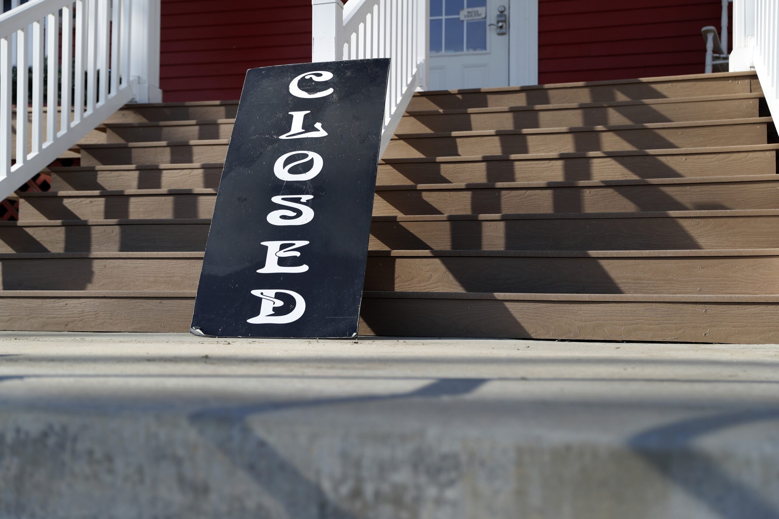 A sign leans against the front steps of a closed business in Kimmswick, Mo