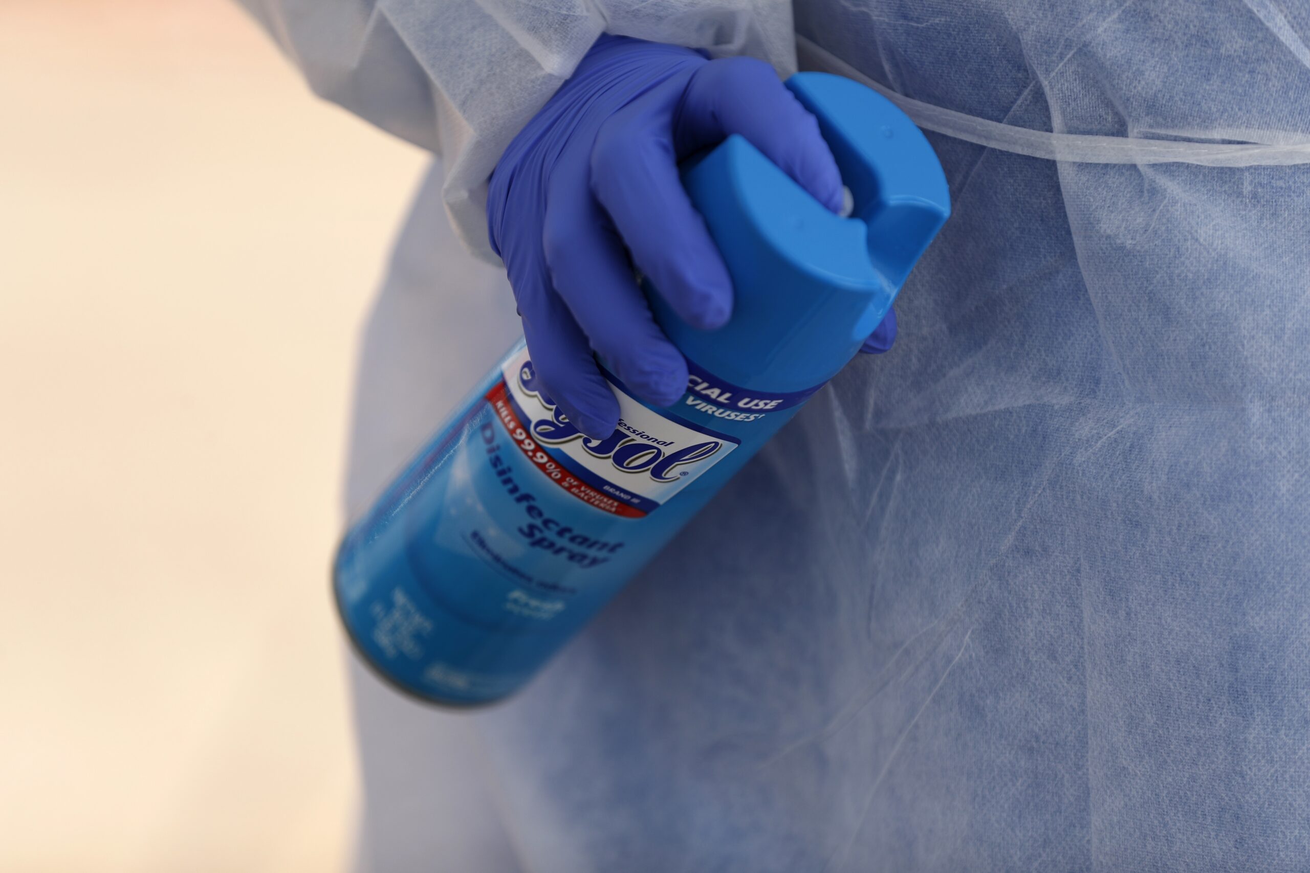 Registered medical assistant holds a can of disinfecting spray as she works at a drive-through COVID-19 testing site
