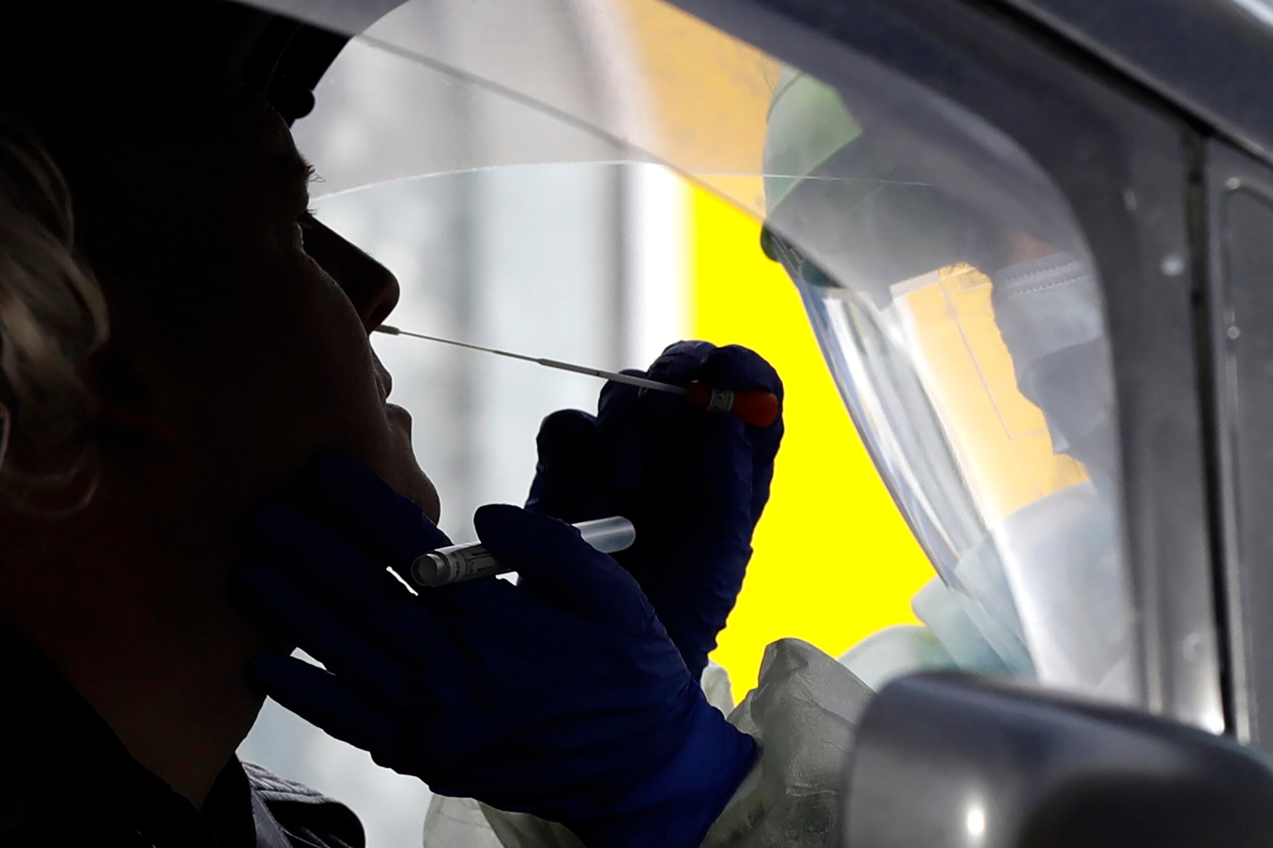 Medical staff test a shopper in his car who volunteered at a pop-up community COVID-19 testing station