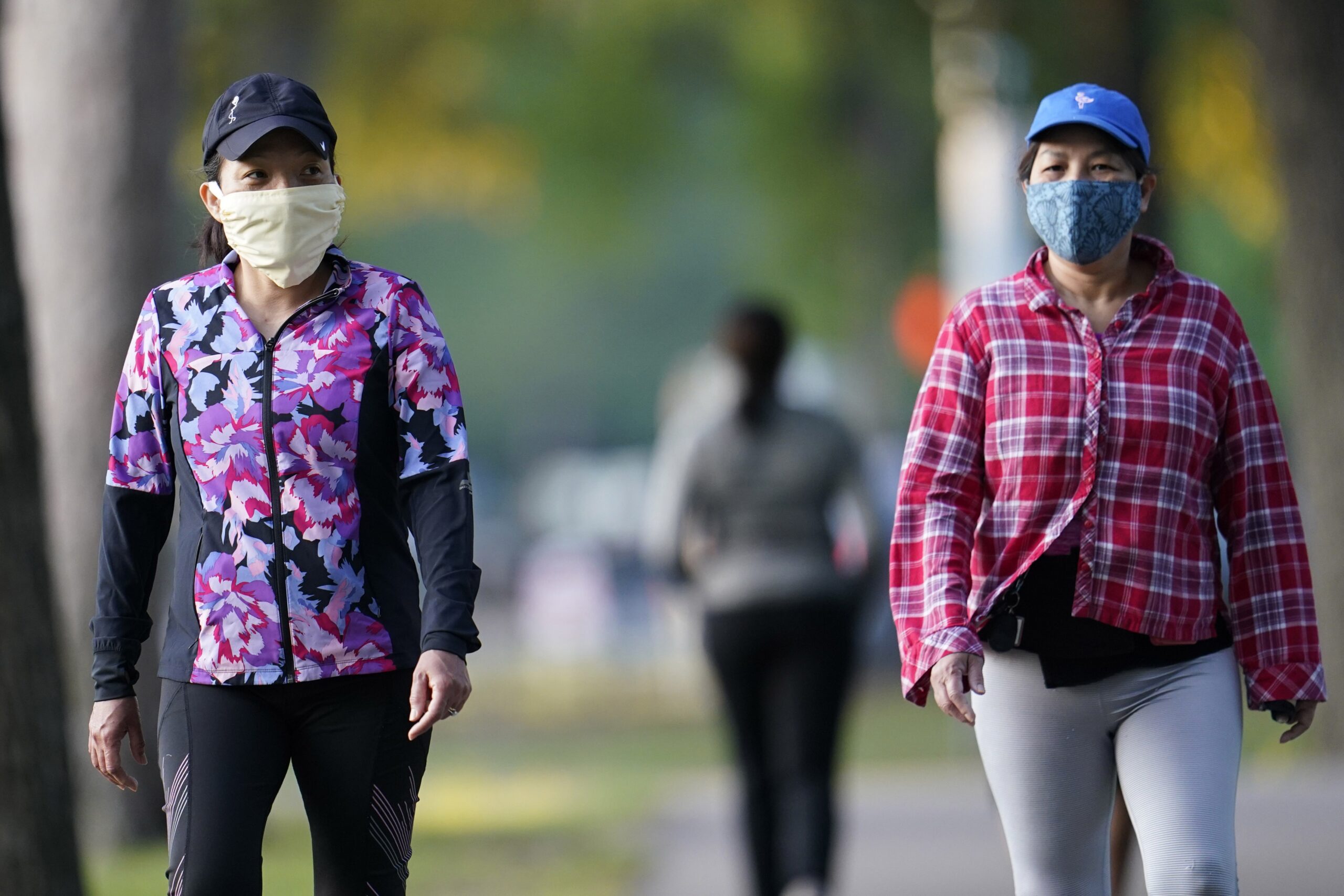 Thu Huynx and Trang Ngyen walk along a park trail while wearing face masks to help prevent the spread of COVID-19