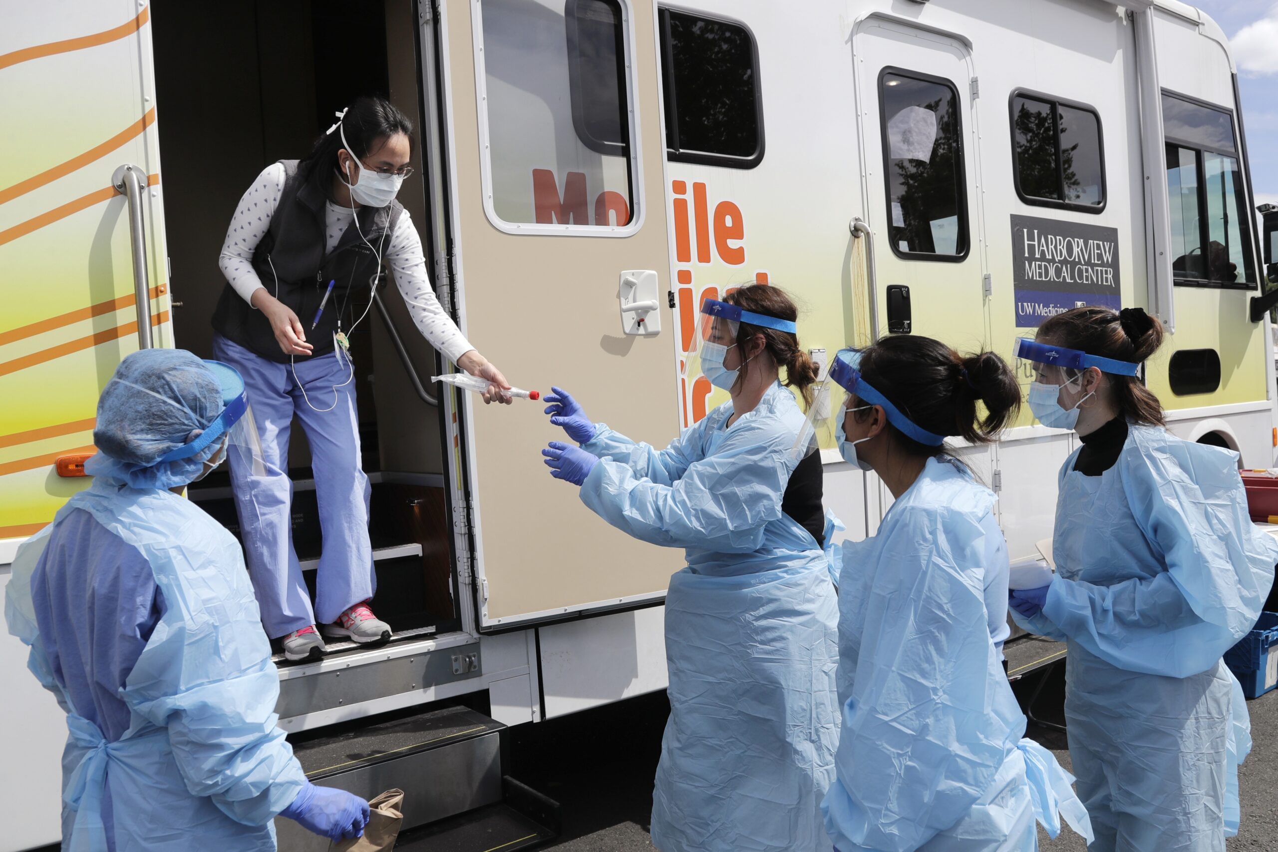 Medical assistants wait to be handed testing kits at a drive-up coronavirus testing site