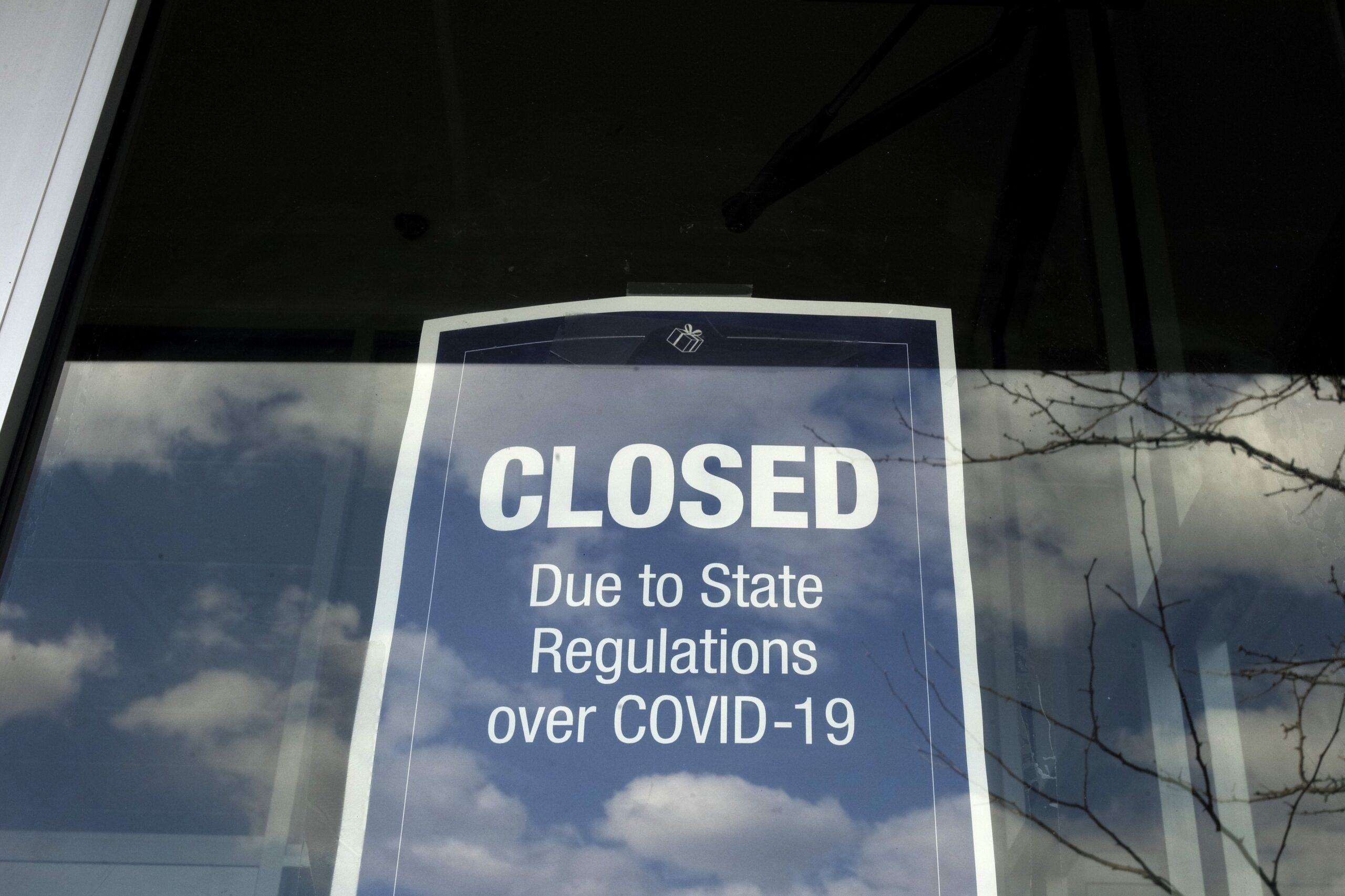 A closed sign is posted in the window of a store because of the coronavirus in Dedham, Mass.