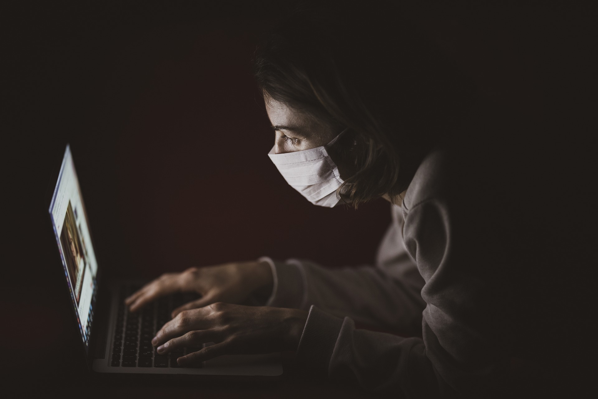 Woman with protective mask, using computer.
