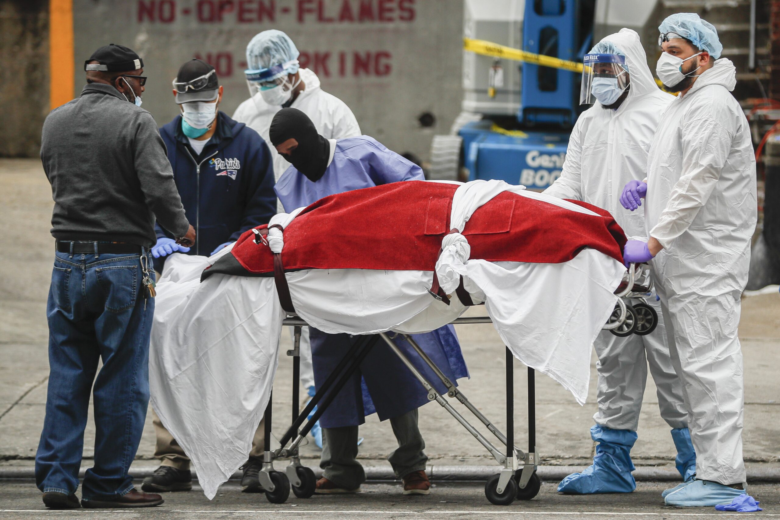 A body wrapped in plastic is handled by medical workers in Brooklyn