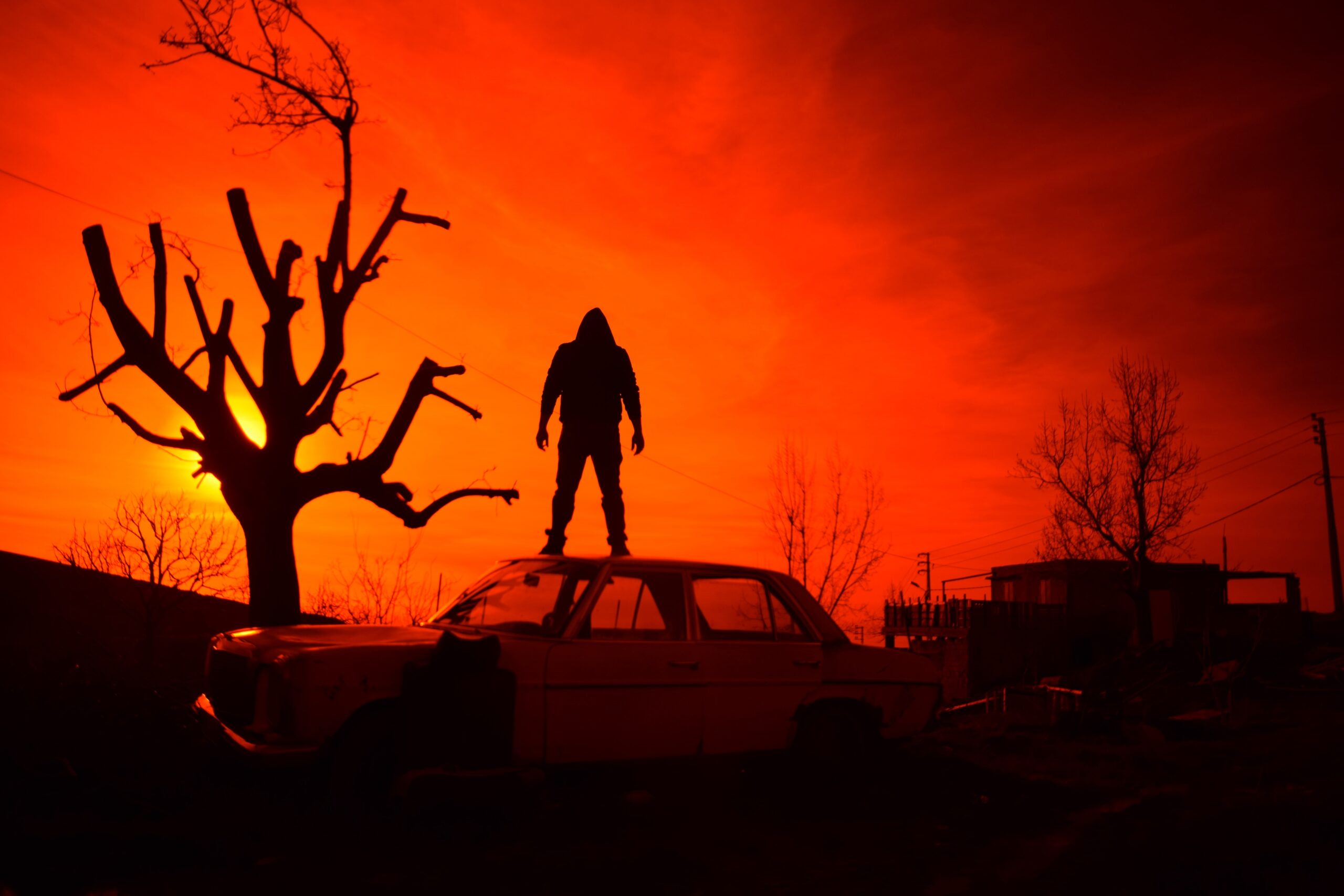 Person standing on car in apocalyptic dusk light