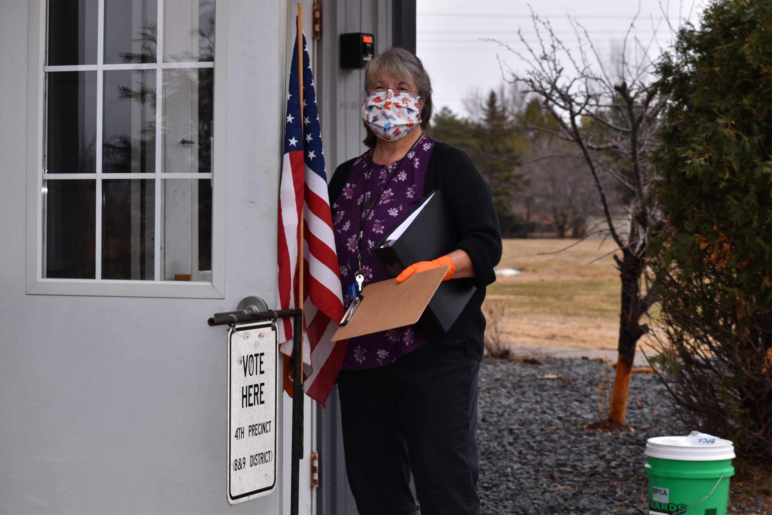Kathy Izzard, donning a mask and gloves, has been helping people vote