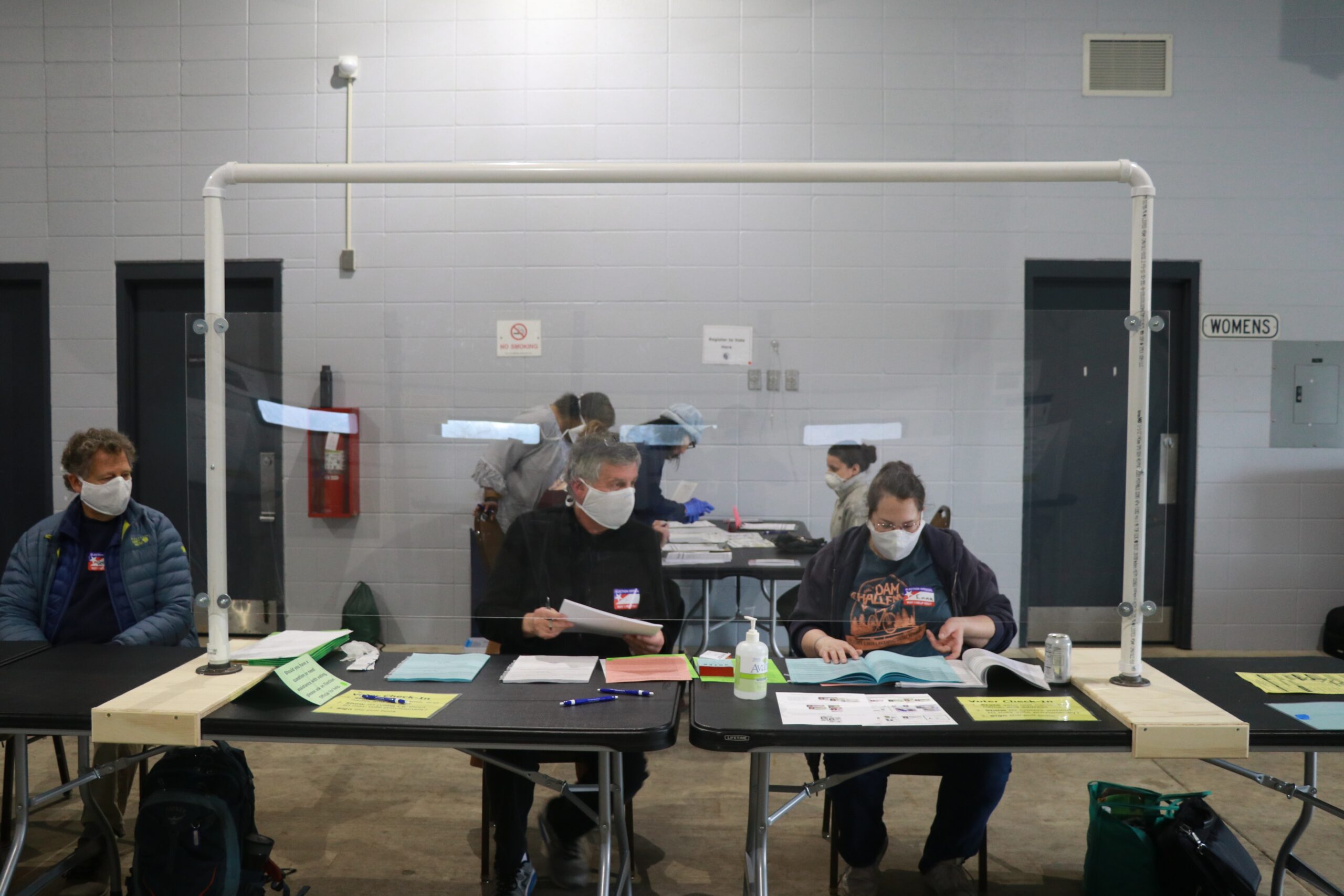 Workers in protective gear staff a polling location