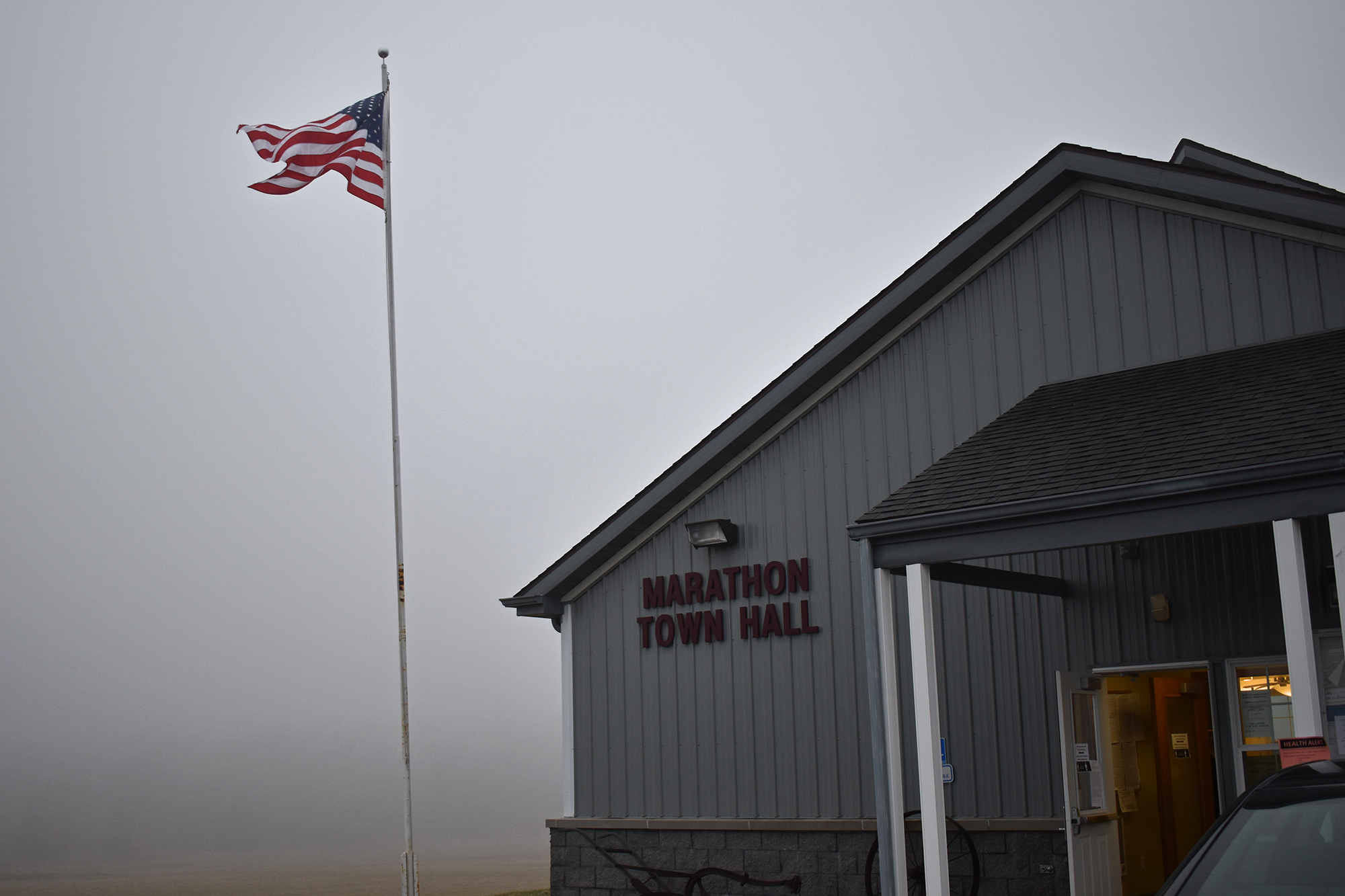 An American flag is visible in the fog outside the Marathon City Town Hall