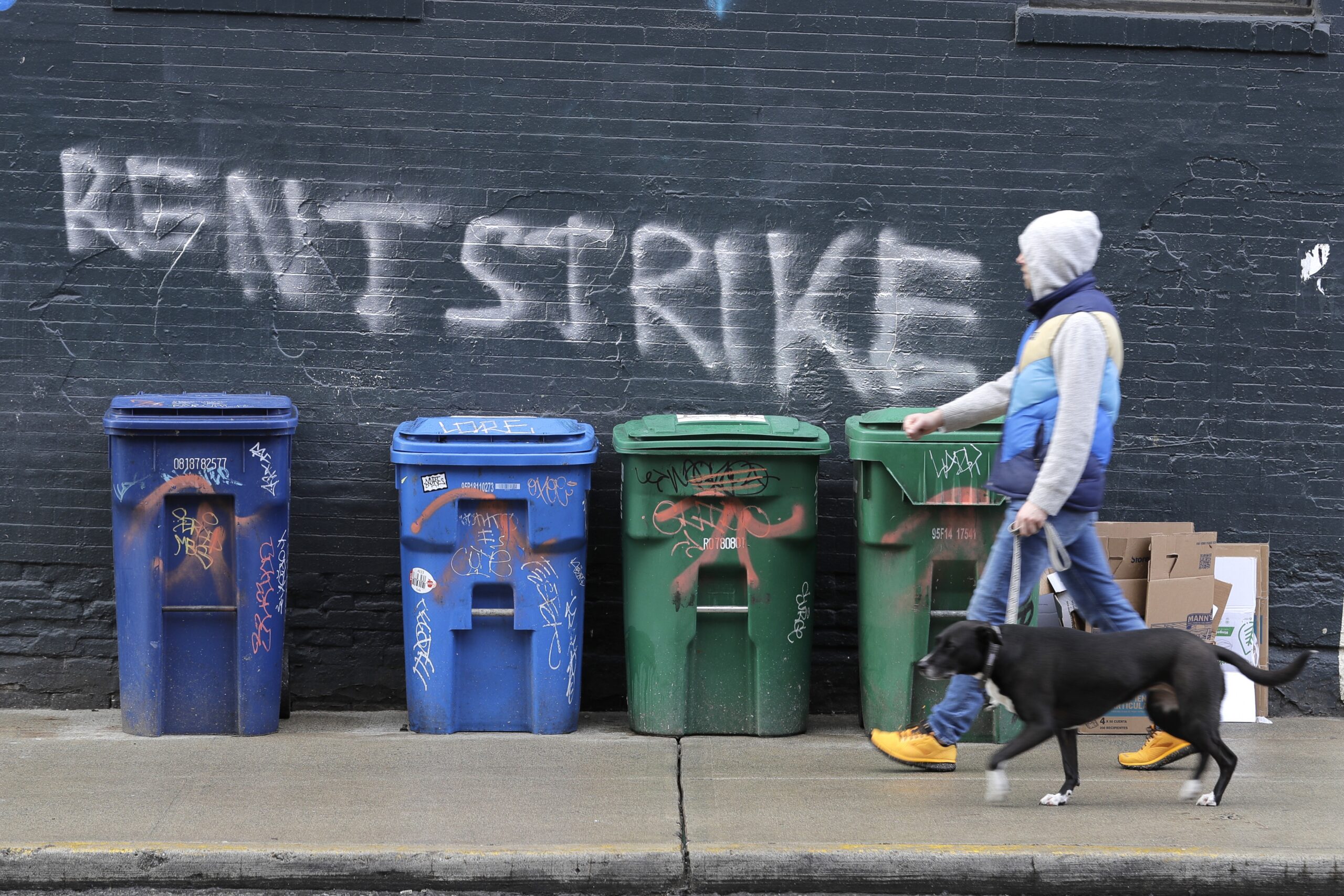 A pedestrian walks past graffiti that reads "Rent Strike"