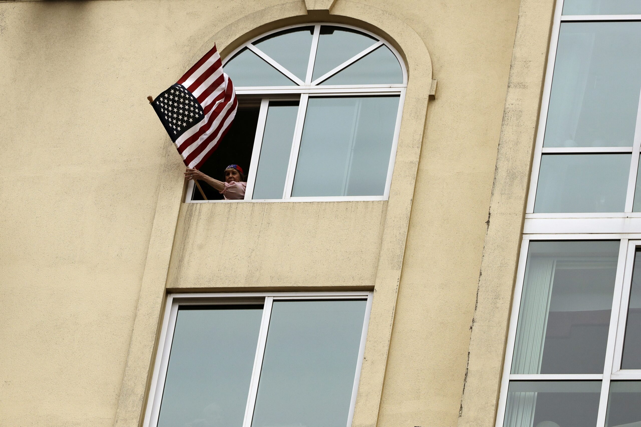 Woman holds flag out a window in quarantine