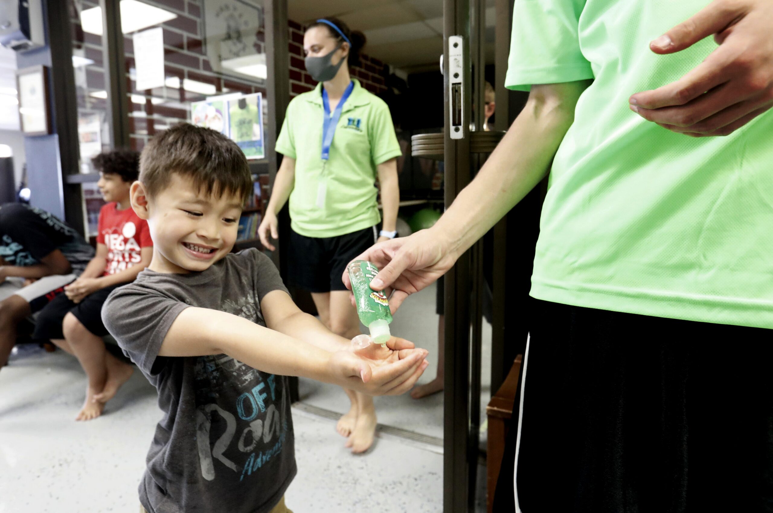 Bruce McCall, 5, smiles as he takes hand sanitizer during martial arts daycare summer camp