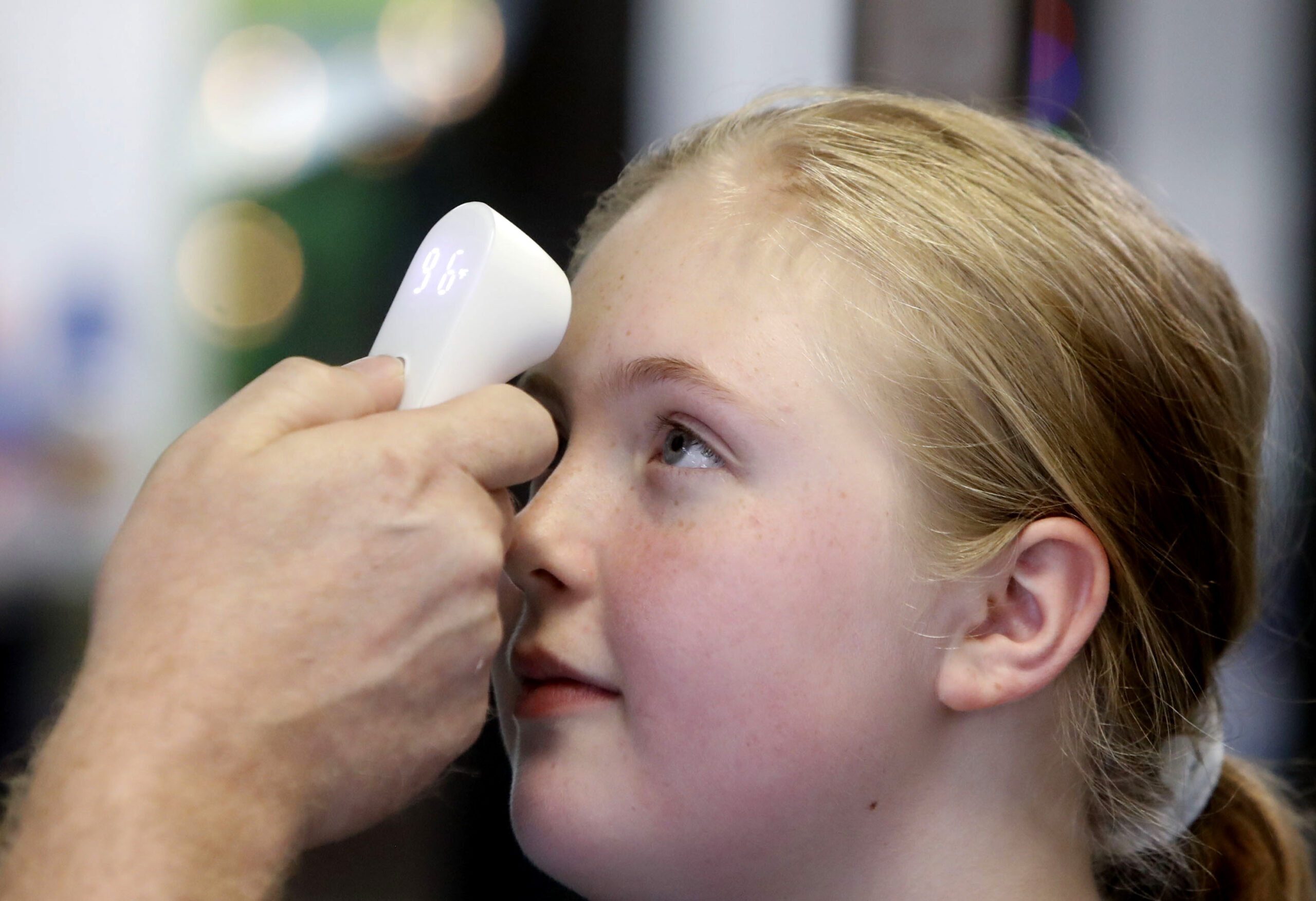 Kaiden Melton, 12, has her temperature taken during a daycare summer camp