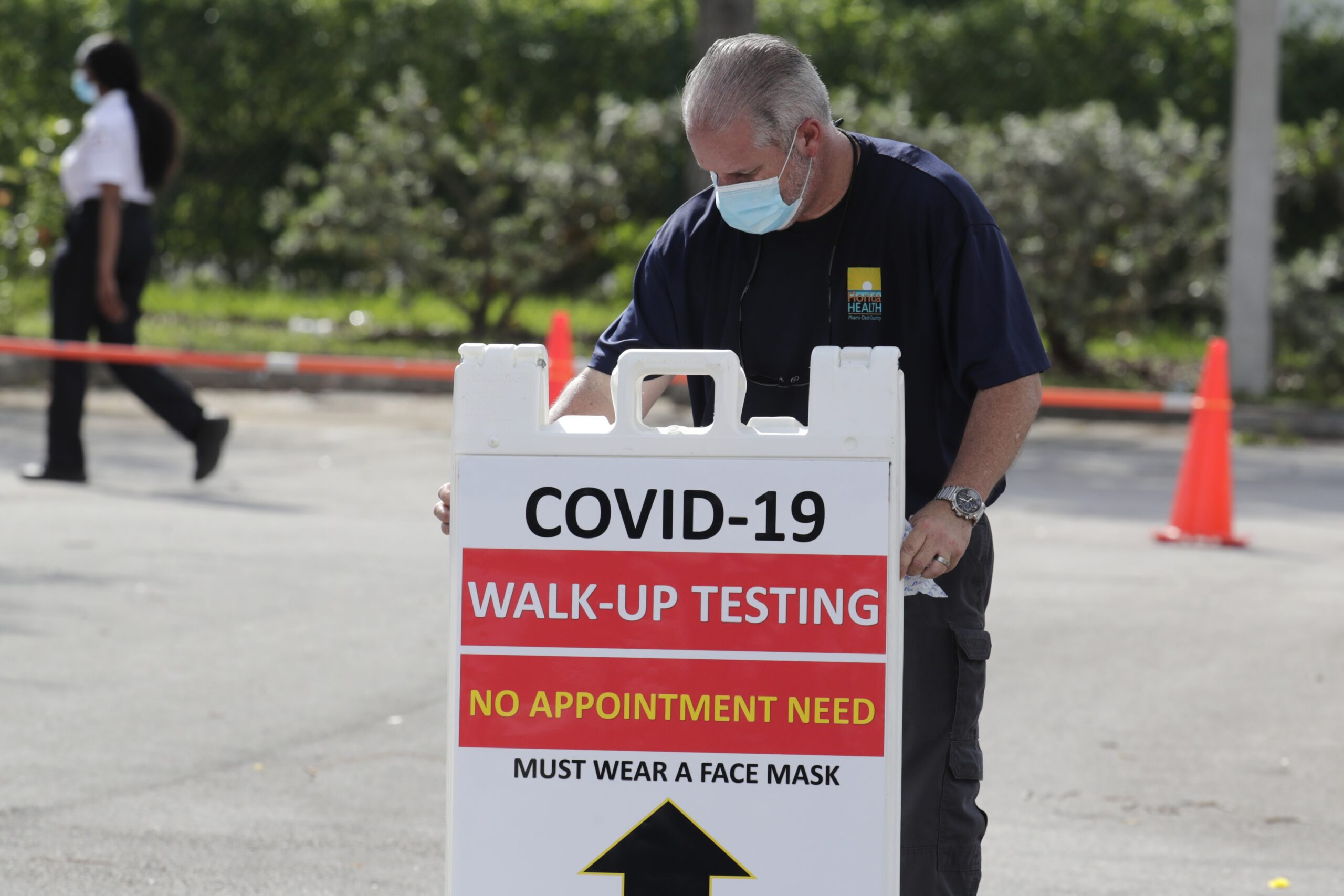 An employee of the Florida Department of Health puts up a sign at a testing site for COVID-19