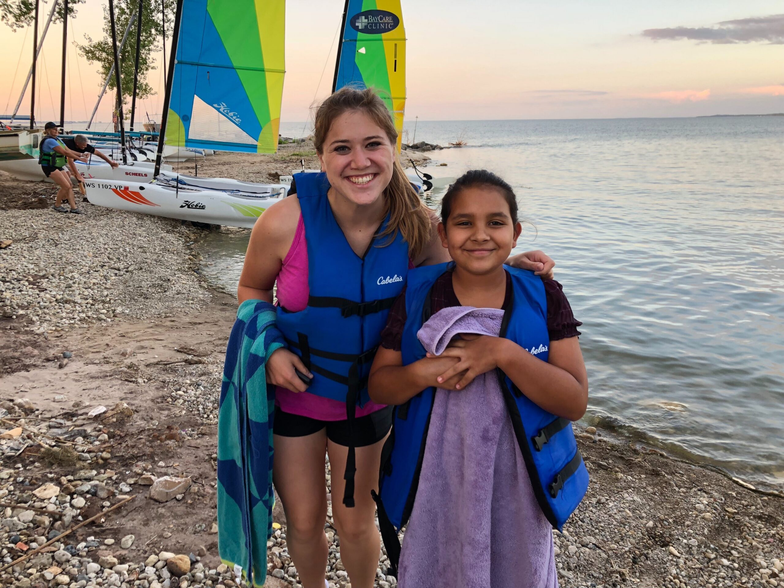 Katie Hermsen and her Little Angelina pose for a photo in front of sail boats