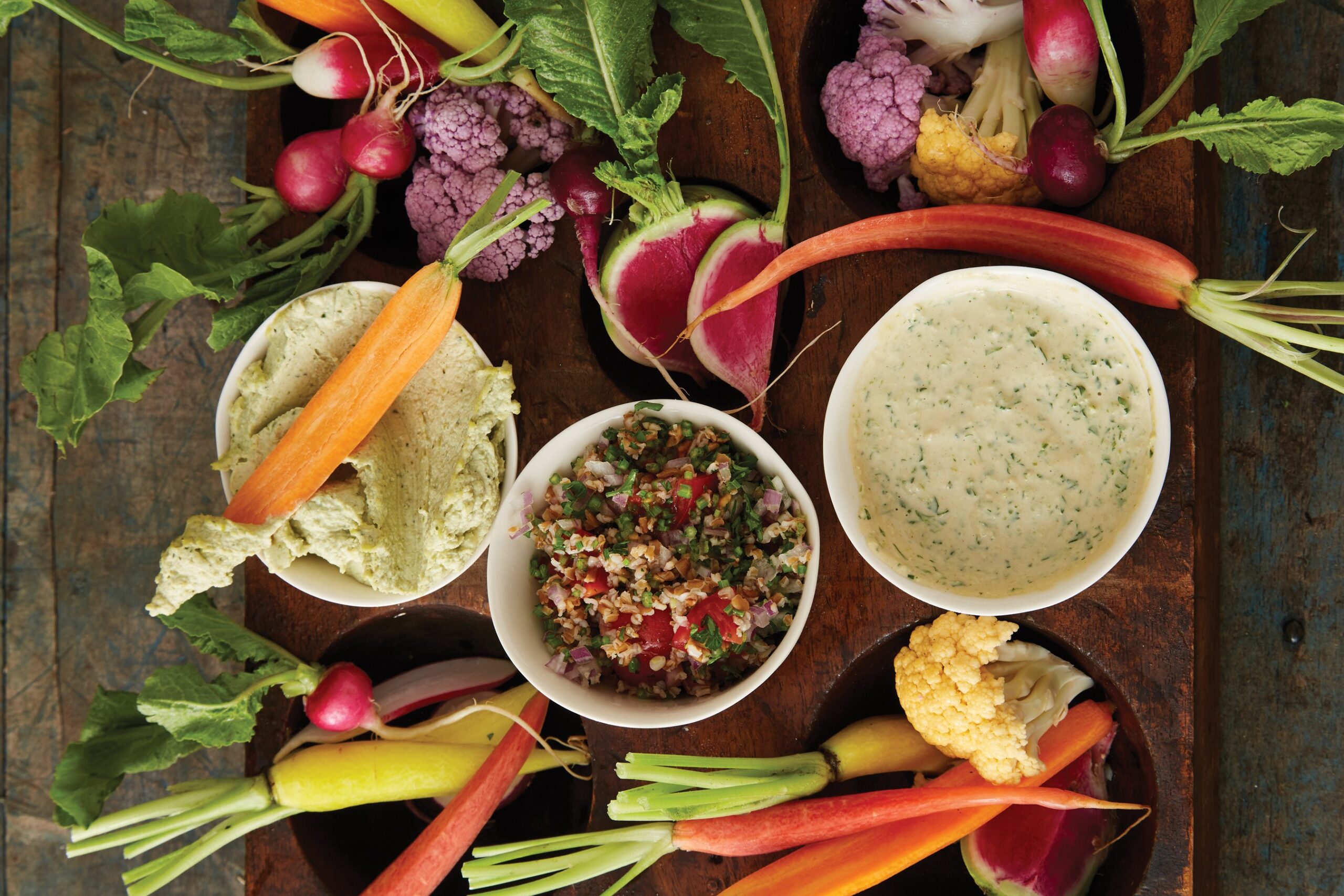 A spread of vegetables and various dips, including Kale Stem Hummus