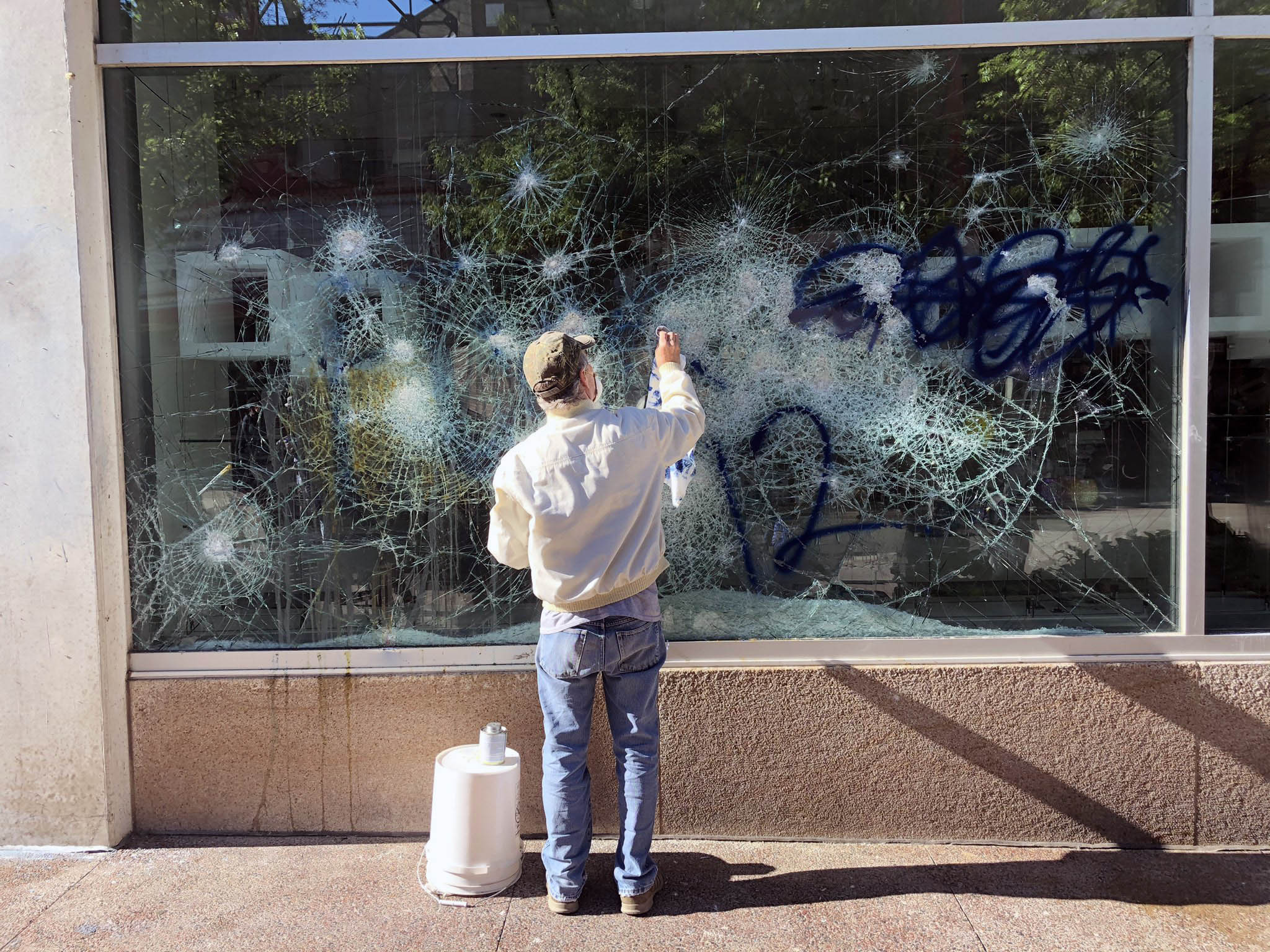 A person tries to clean and repair a window of the Museum of Modern Art store