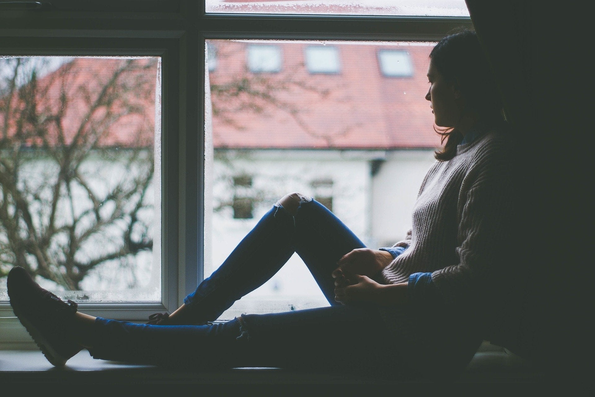 Woman sitting in window looking out.