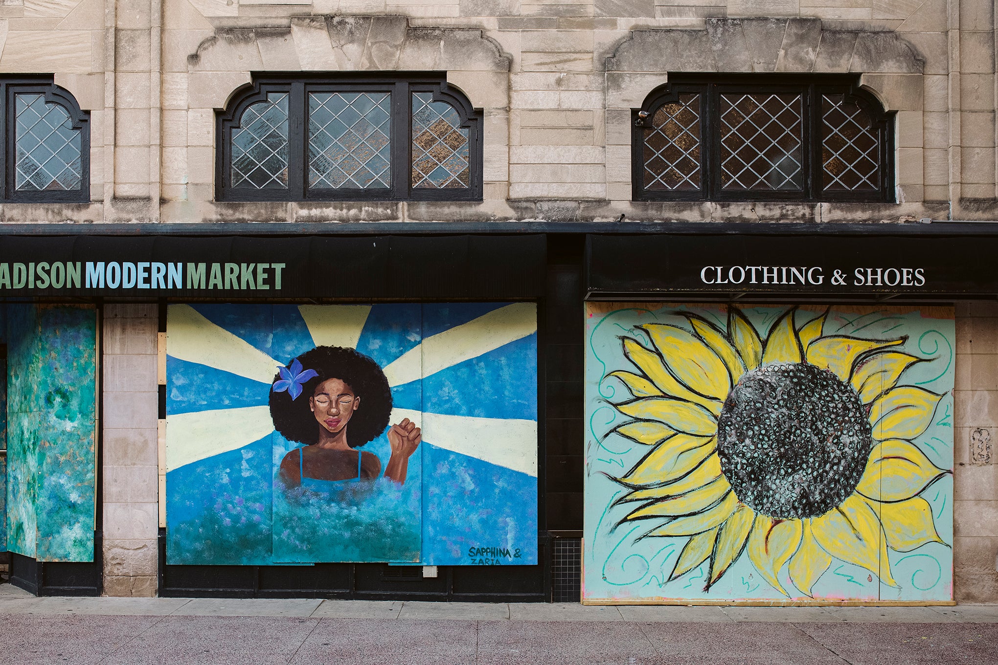 Artwork by Sapphina and Zaria is displayed on boarded up store windows on State Street