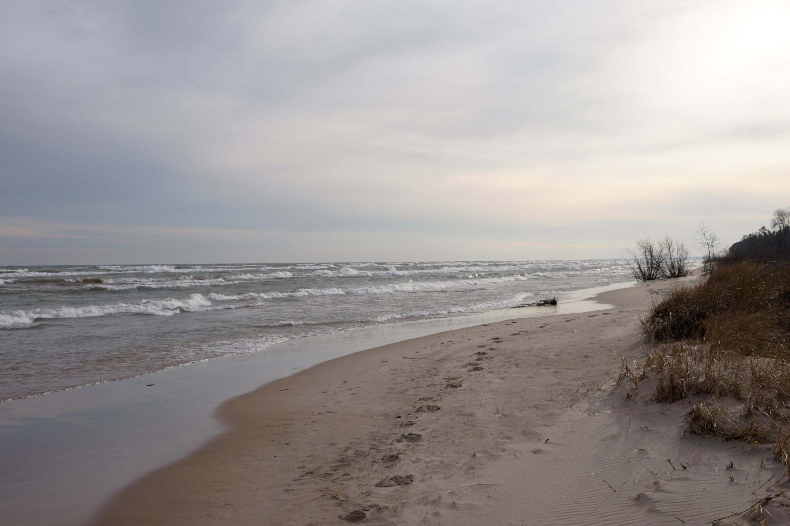 A picture of the sandy beach along the shore of Lake Michigan with foot prints in the sand.