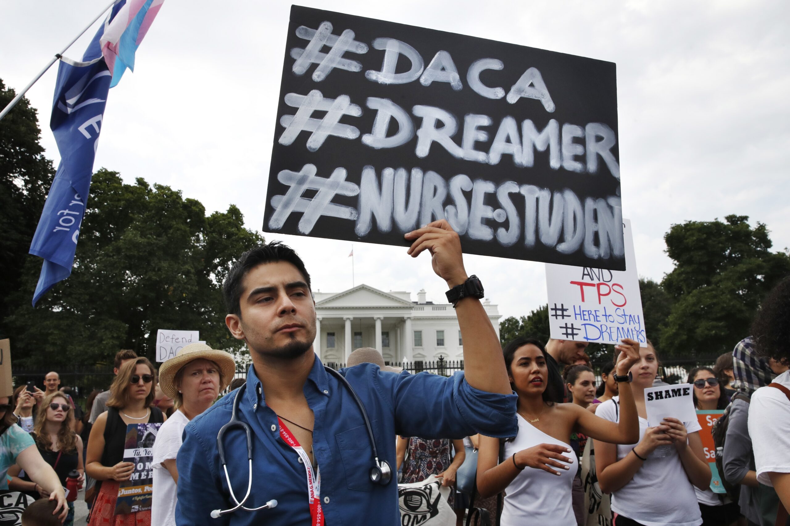 man holds up sign at a protest against depealing DACA