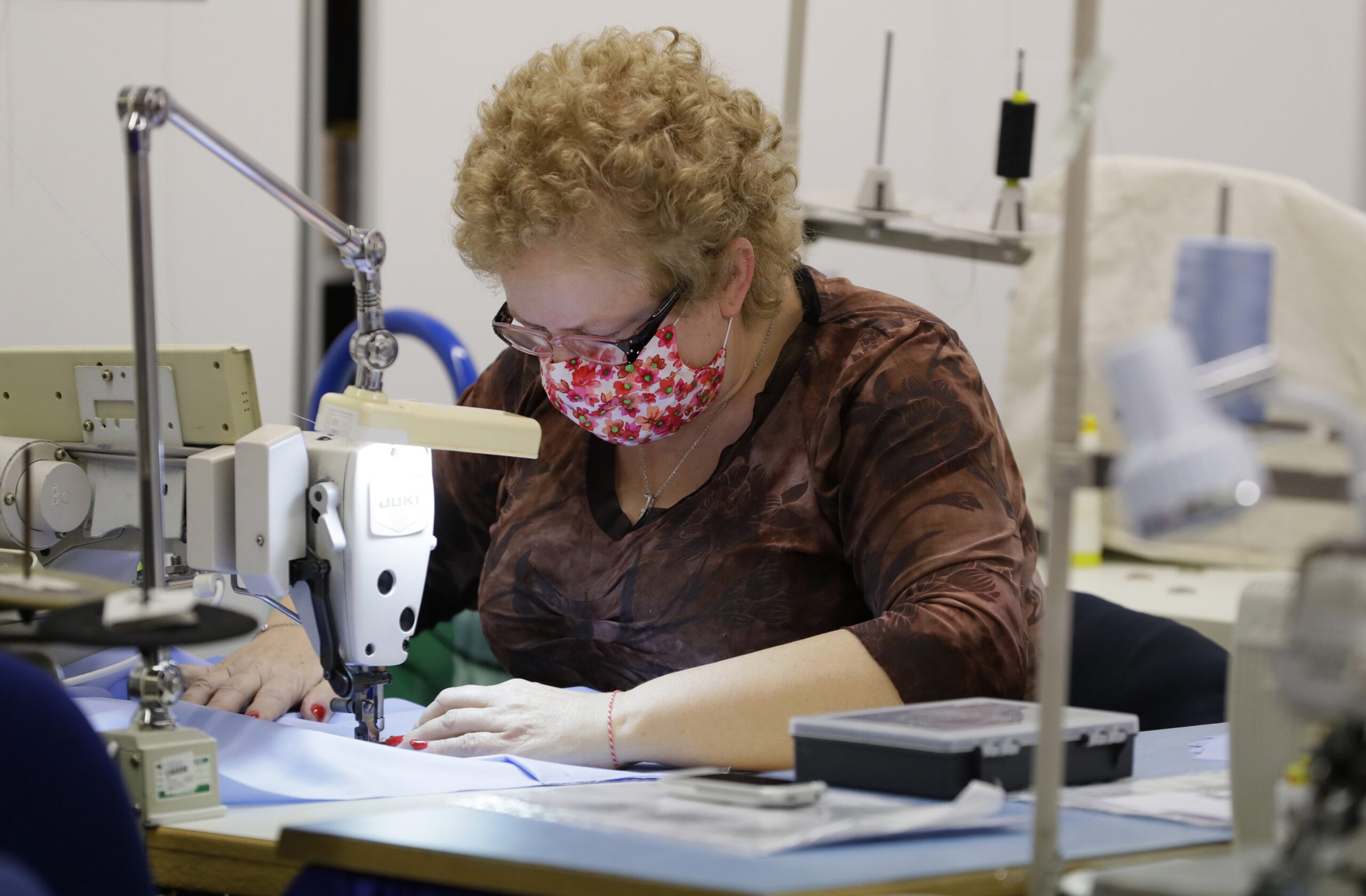 A woman sews face masks in a factory that usually makes clothes