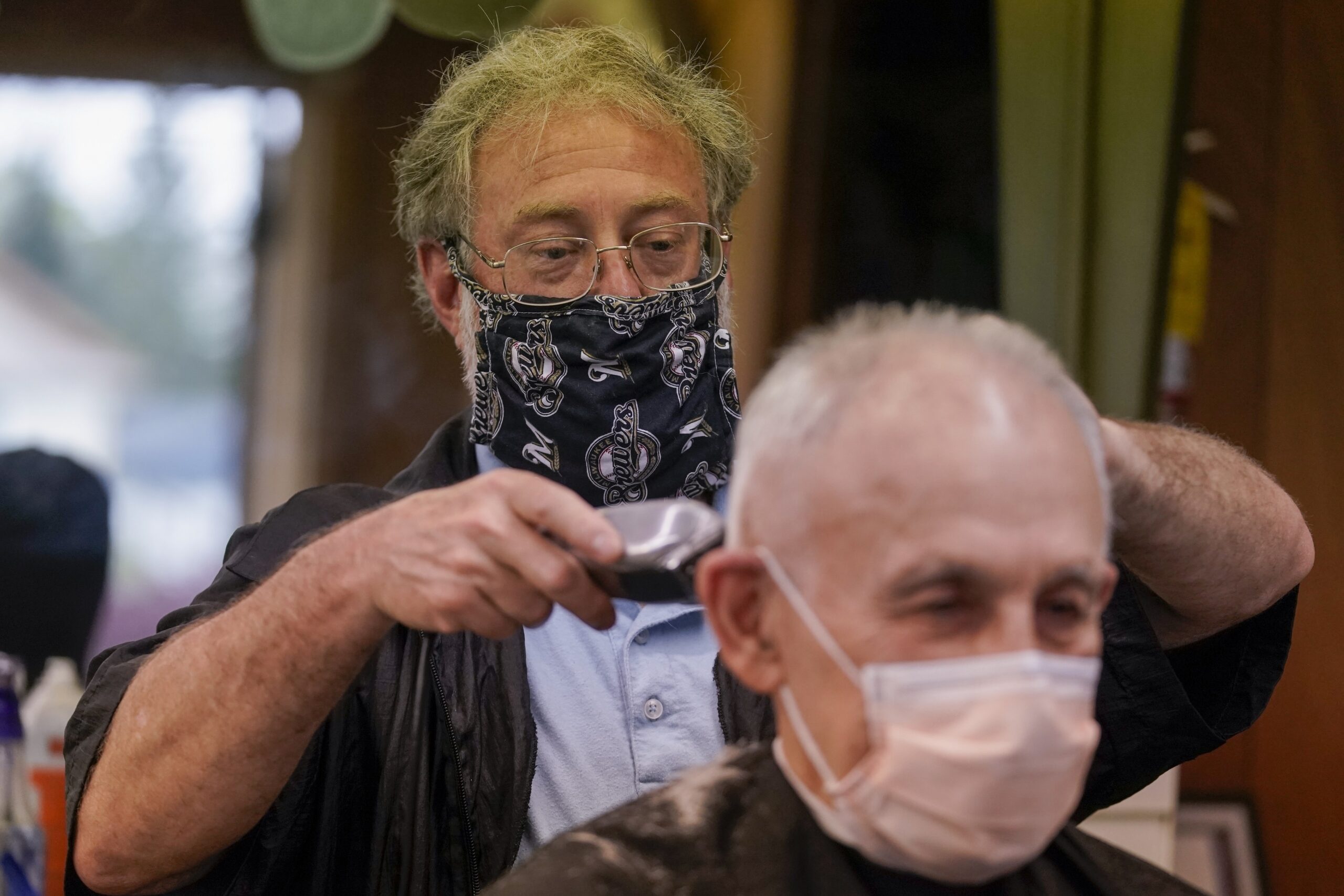A barber wears a mask as he cuts hair