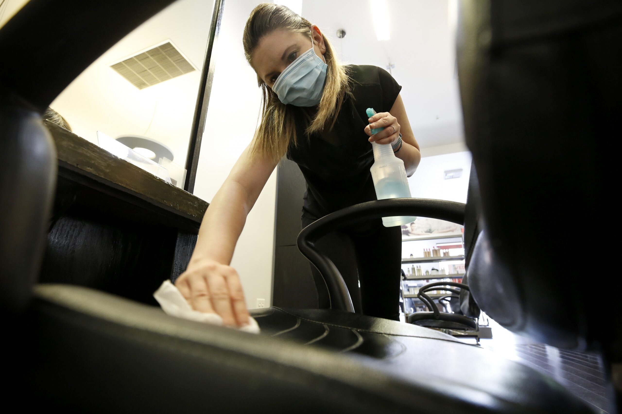 Michaela Kouvelas sanitizes a styling station at the Willo Aveda Salon