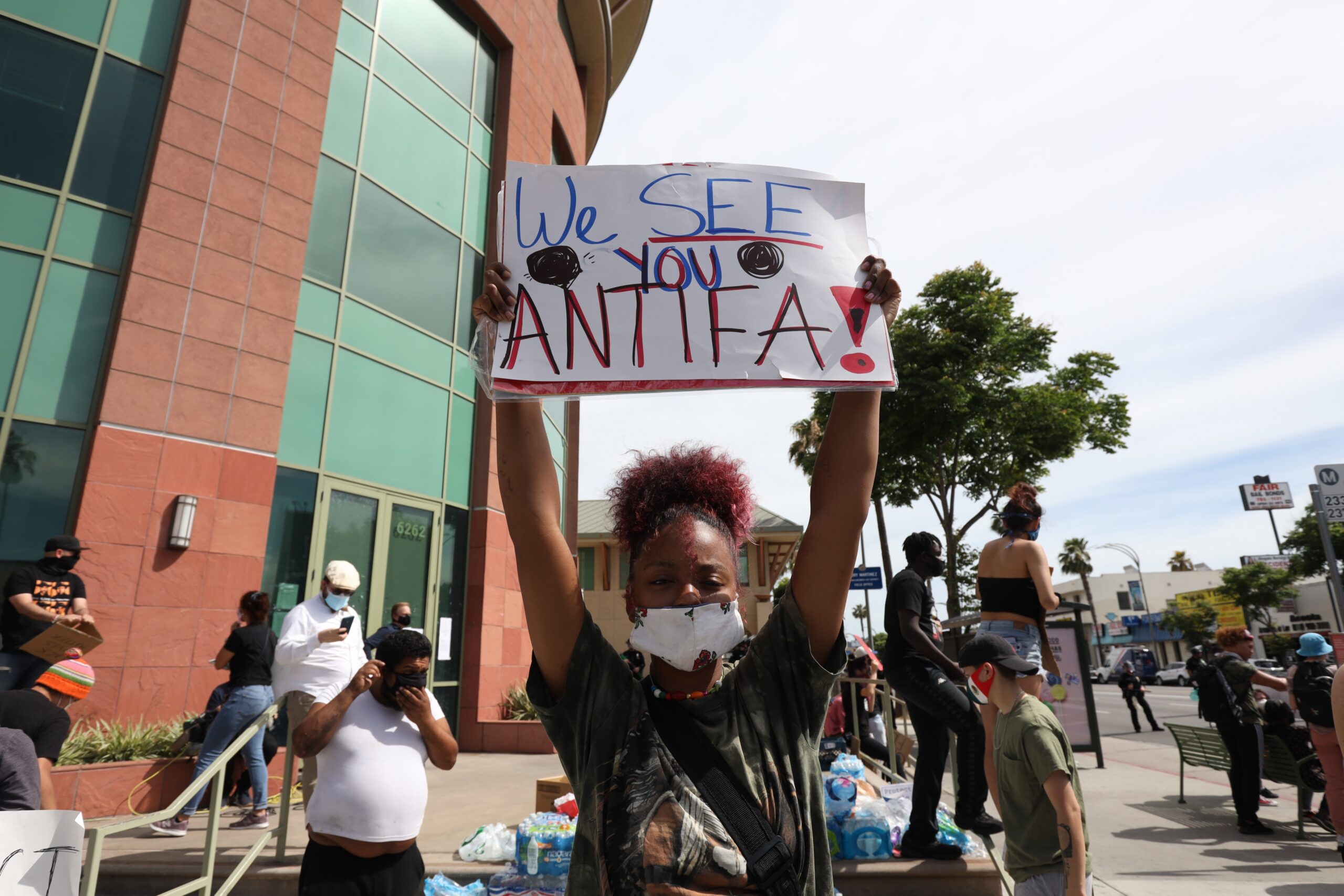 A woman holds a sign addressing ANTIFA at a protest in Los Angeles