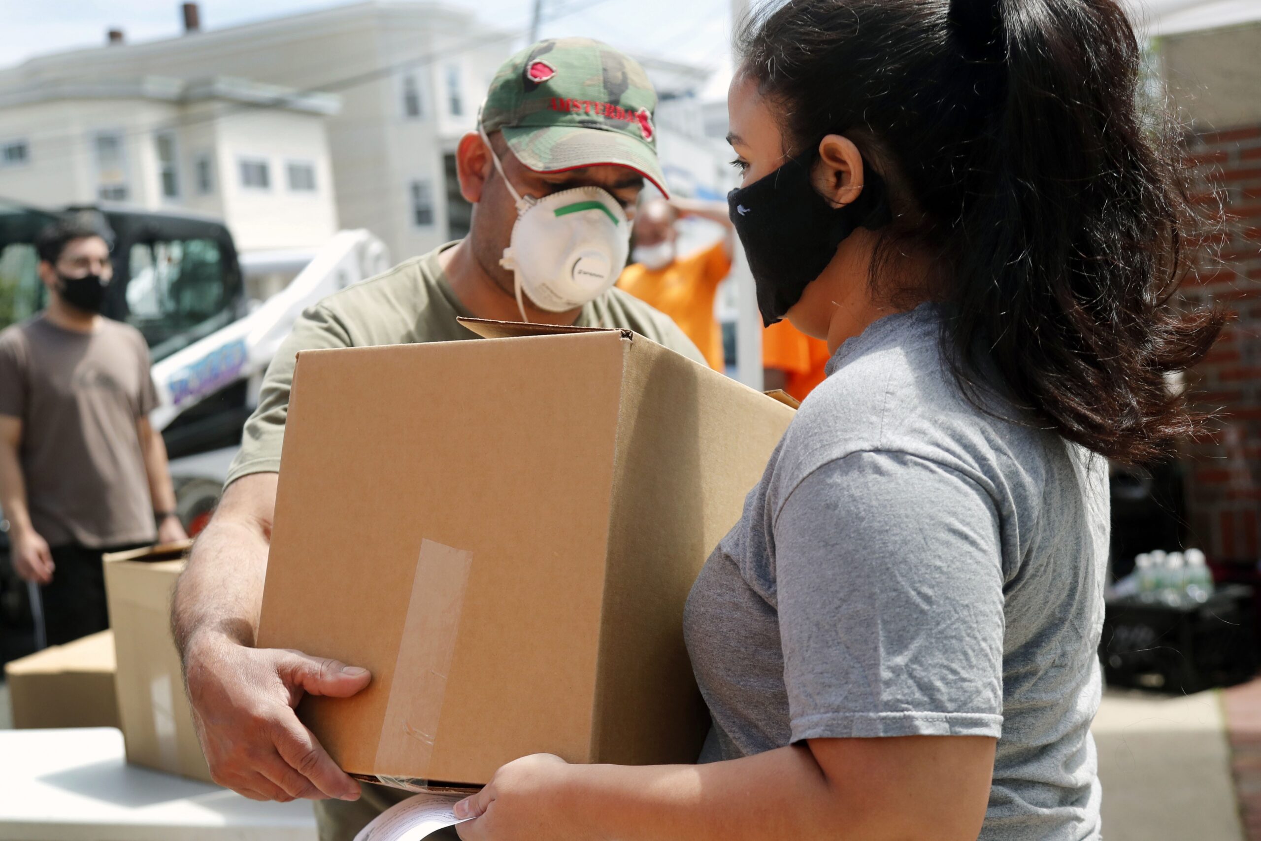 A woman receives a box of food at a pop-up pantry in Chelsea, Mass