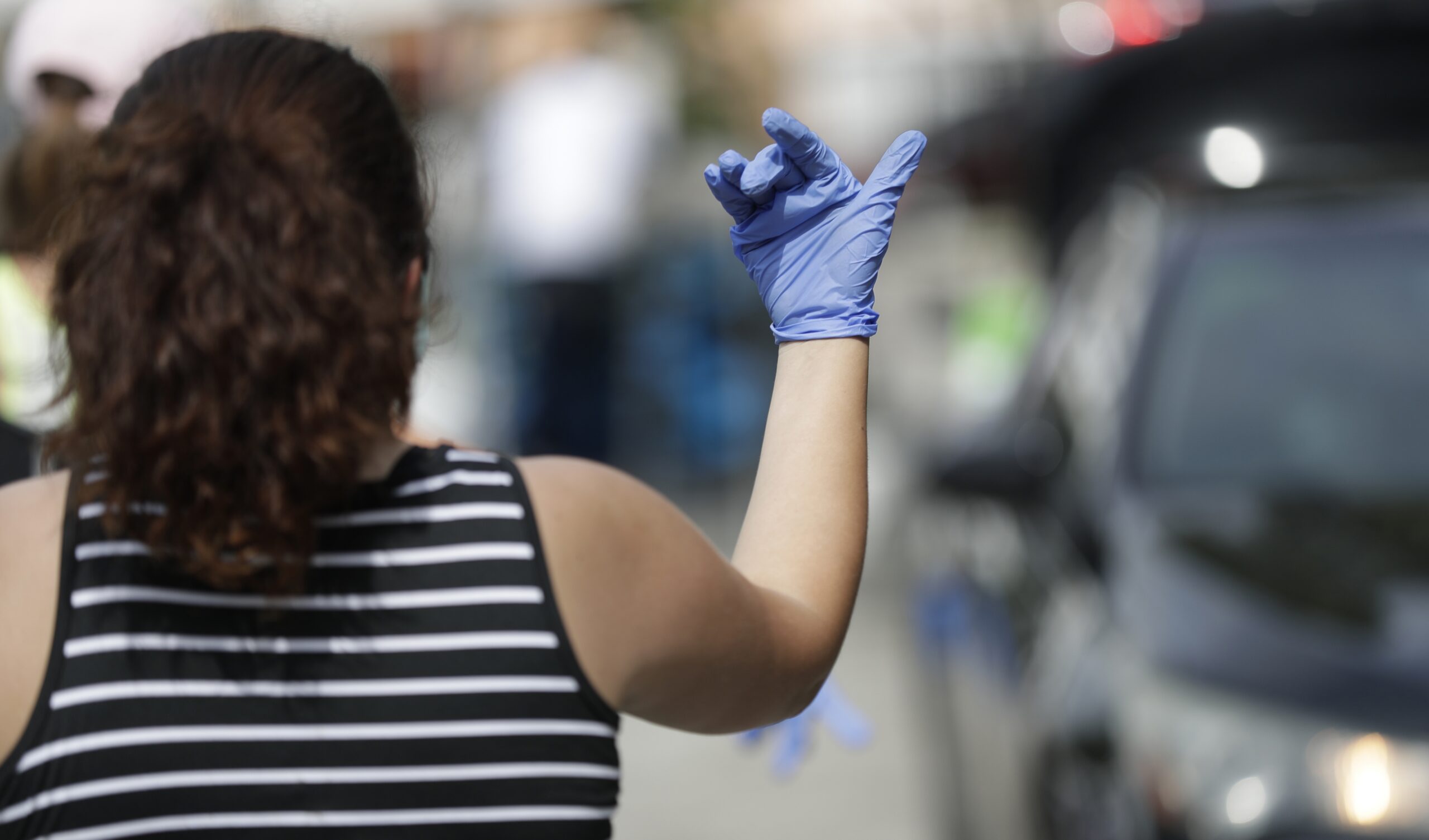 Andrea Hammond signals a car to move forward so that workers and volunteers can load boxes of food into cars