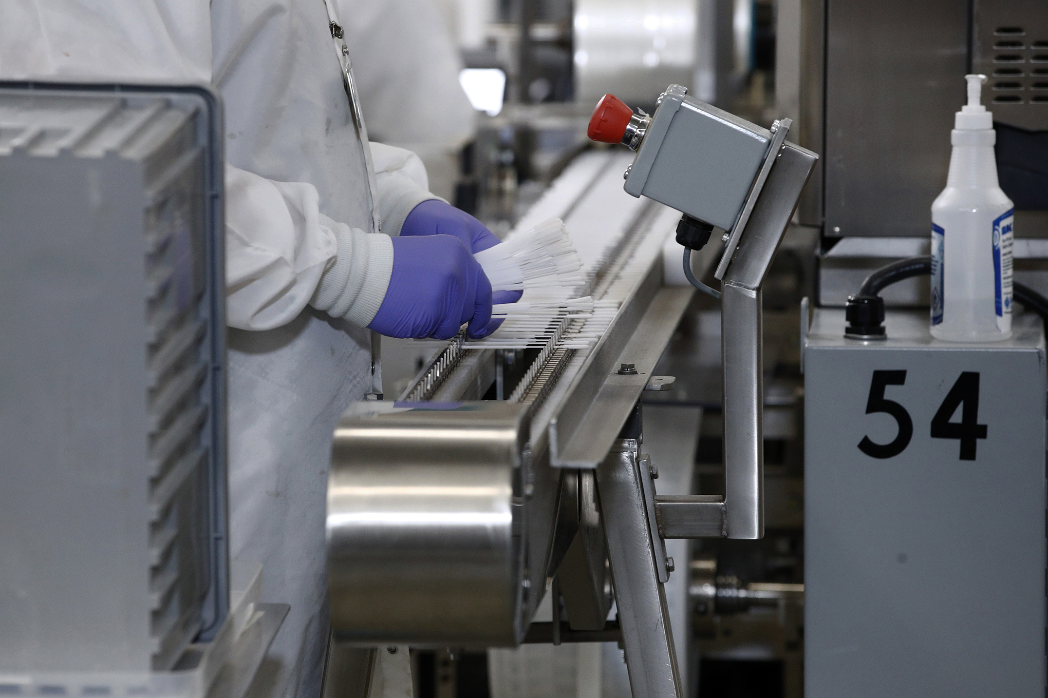 A worker places COVID-19 test swabs on a machine